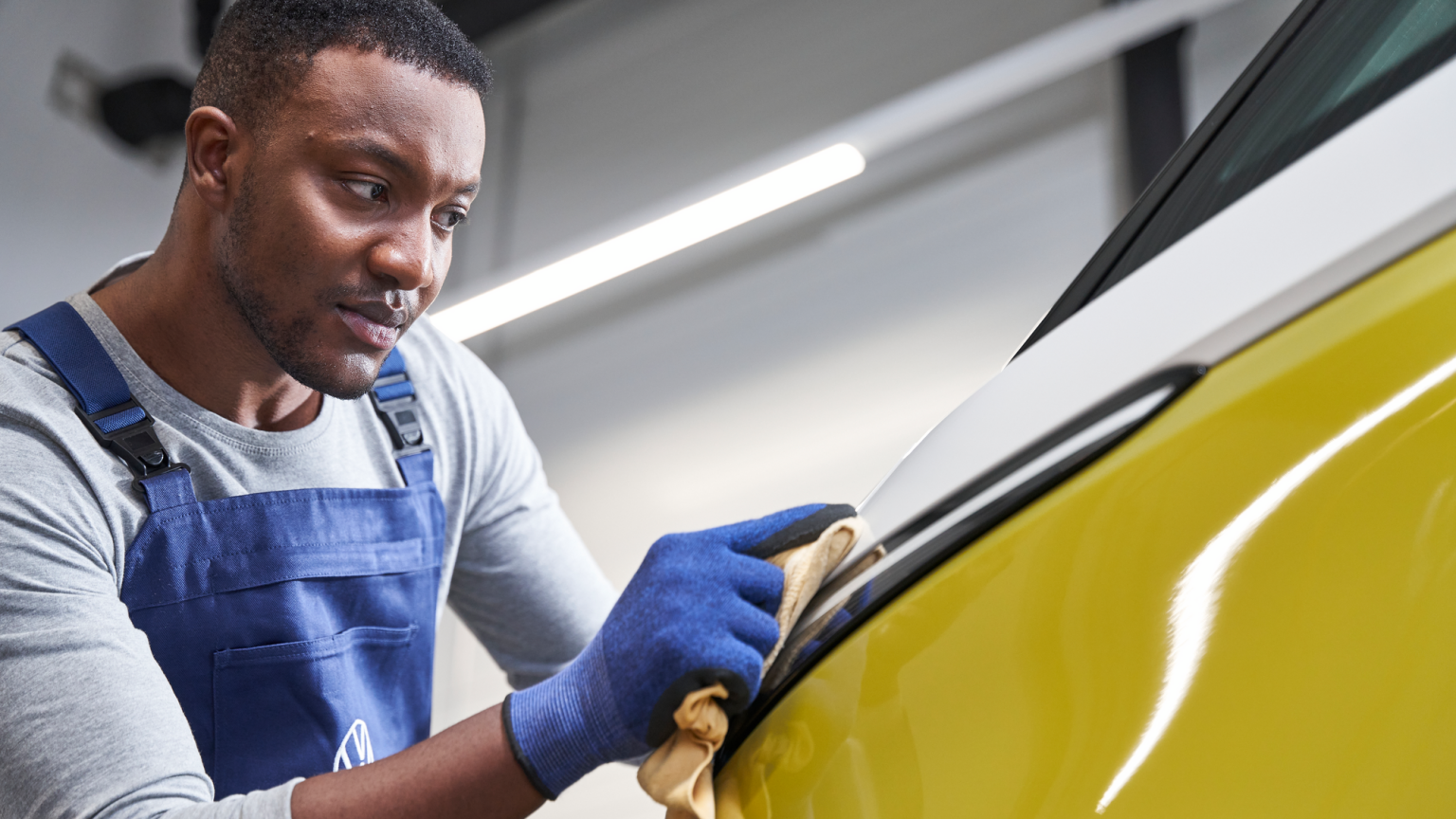 Mechaniker poliert VW gelb-weißen Bulli