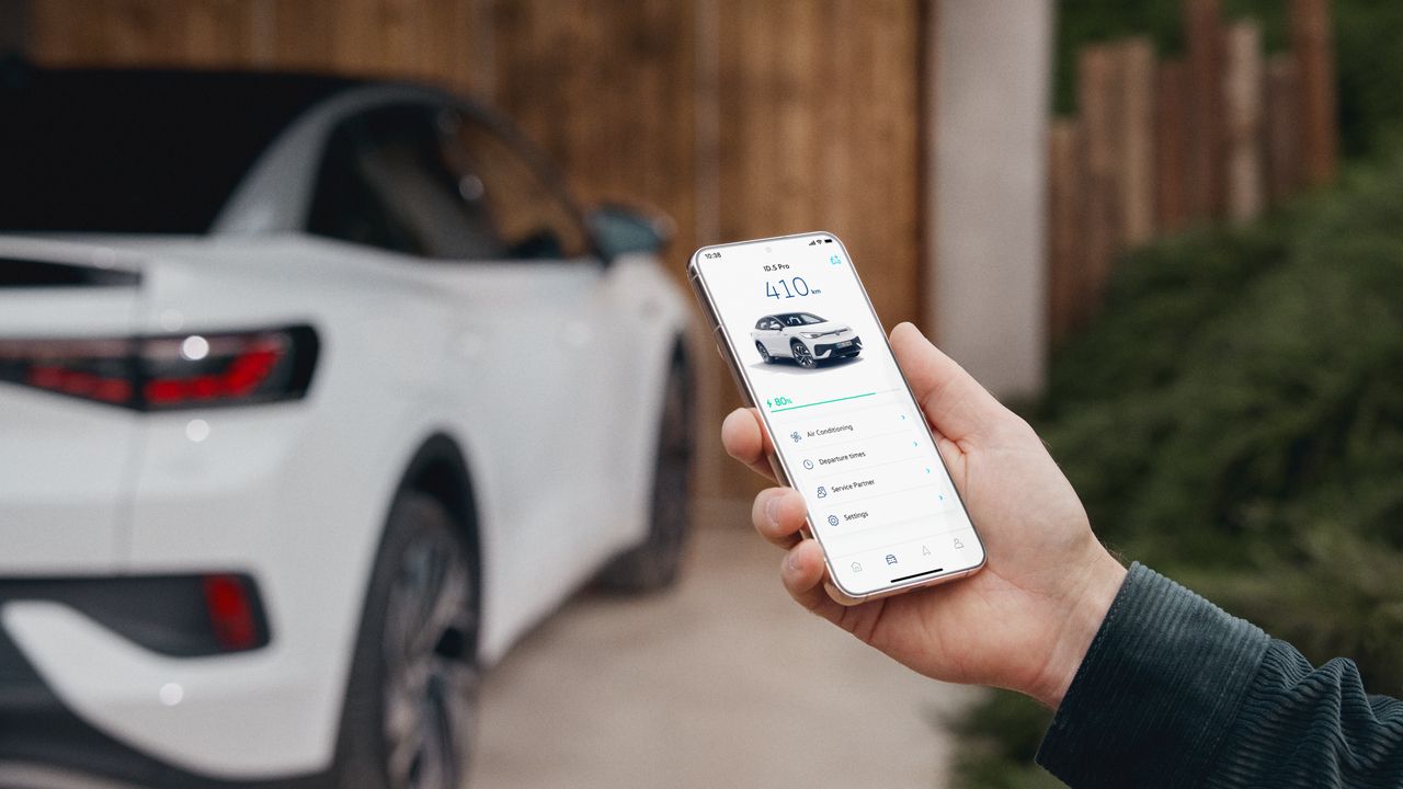 Mann hält Smartphone in der Hand, auf dem Bildschirm sieht man die VW Connect für ID. App, im Hintergrund steht ein weißer ID.5