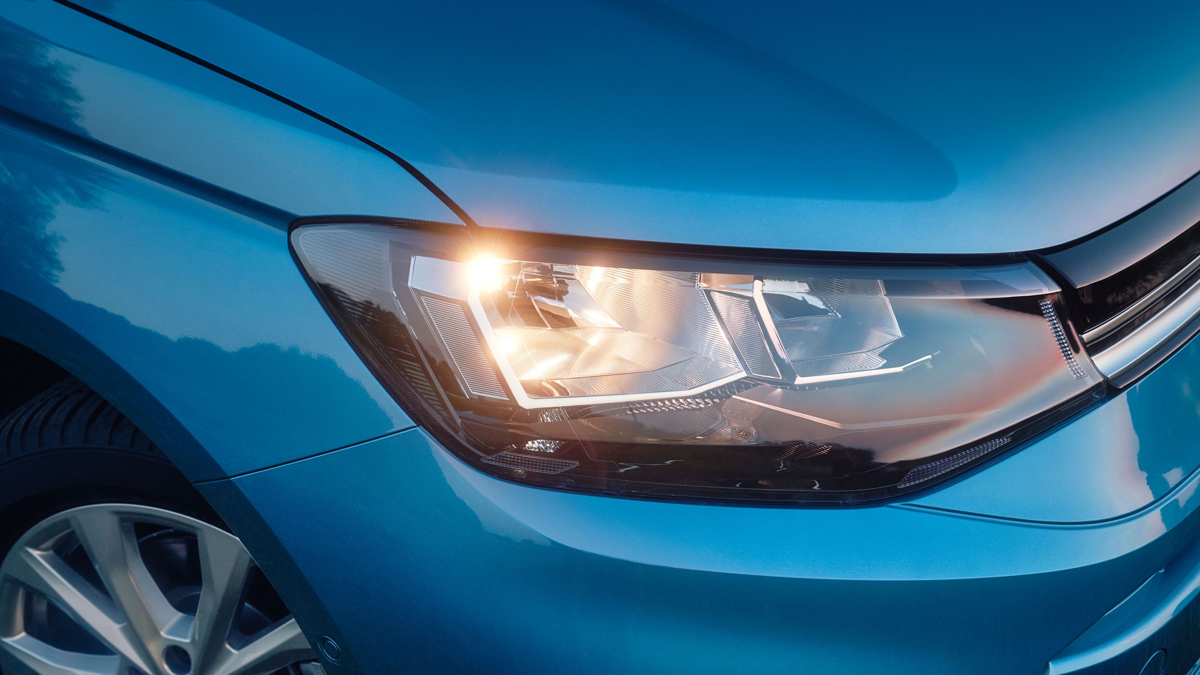 Zu sehen ist ein LED-Scheinwerfer eines blauen VW Caddy.