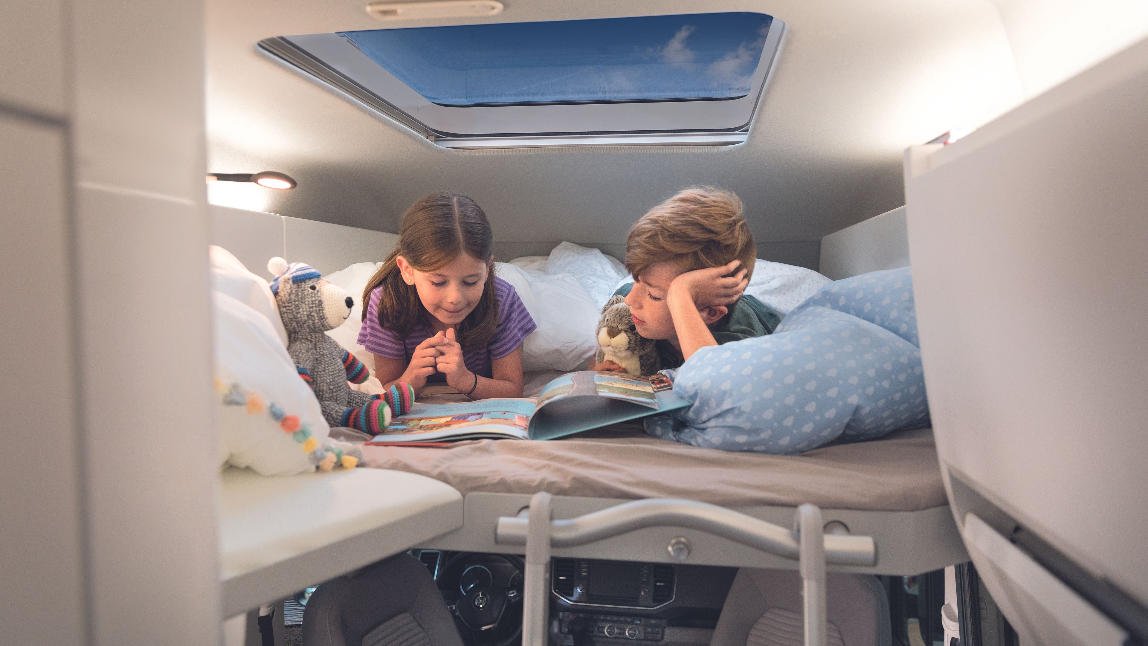 Zwei Kinder liegen auf dem Heckbett im VW Grand California.