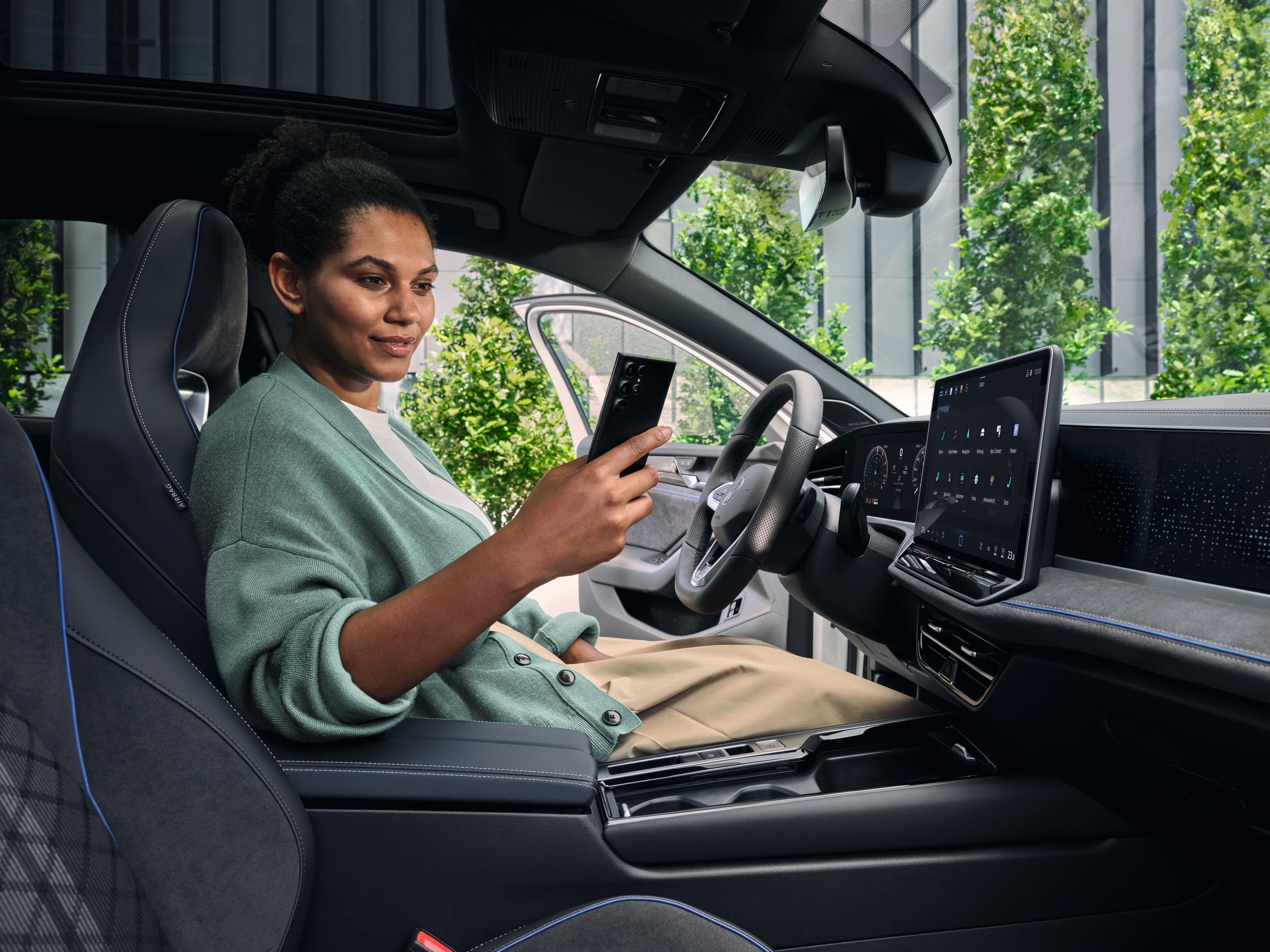Frau sitzt im VW Passat R-Line und blickt auf ihr Smartphone