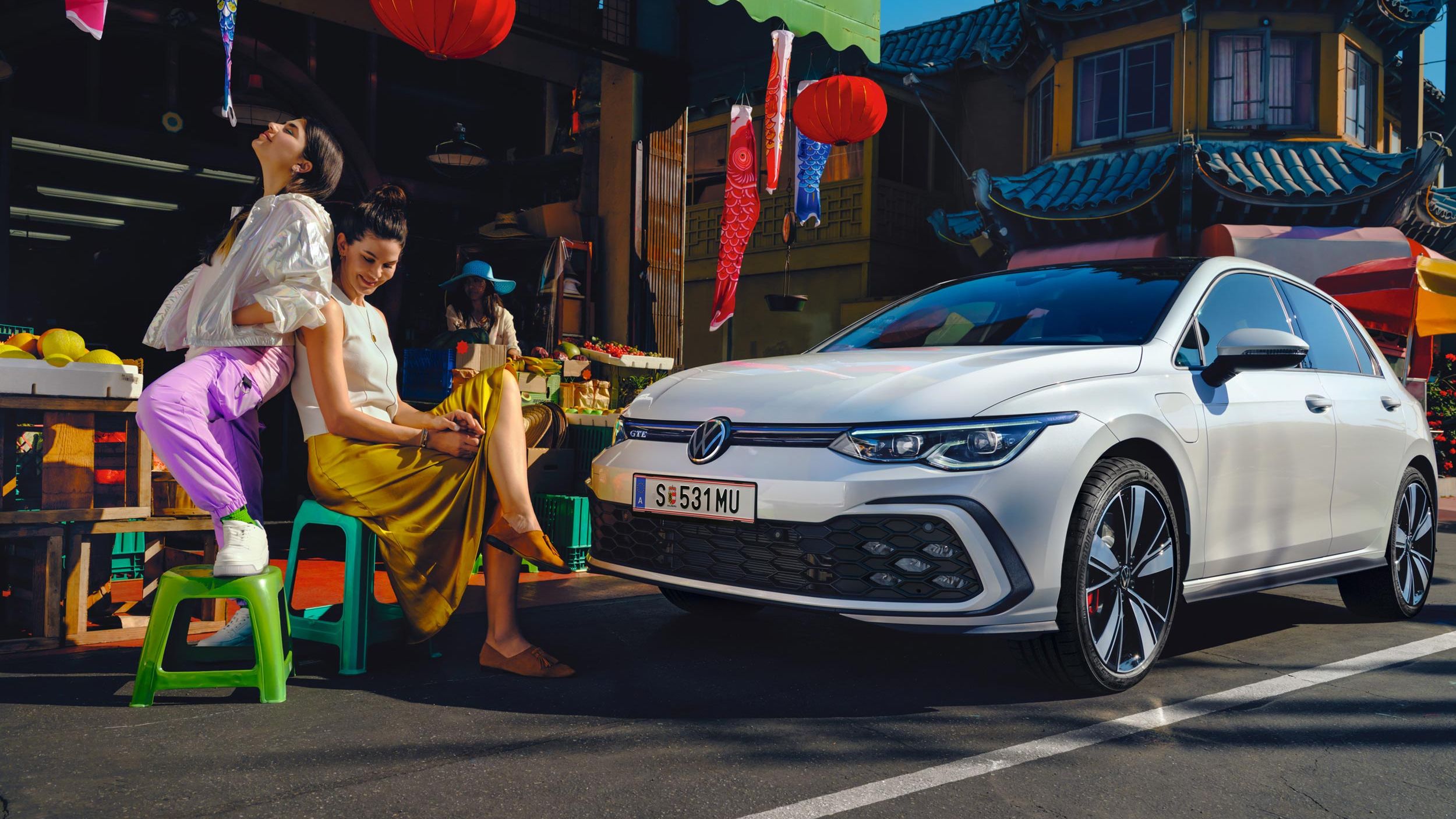VW Golf GTE Seitenansicht steht auf einer Straße, davor sitzen 2 Frauen