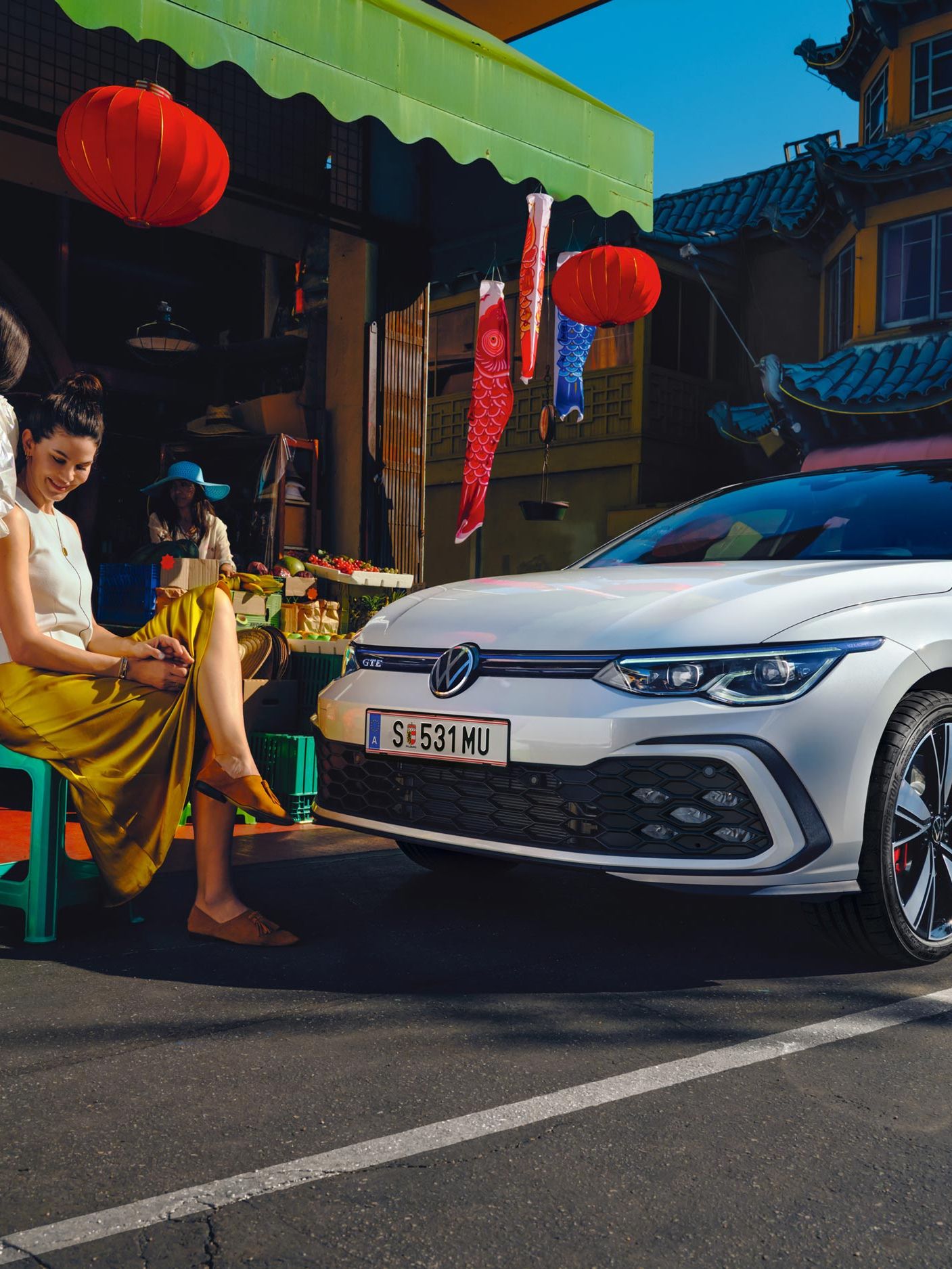 VW Golf GTE Seitenansicht steht auf einer Straße, davor sitzen 2 Frauen