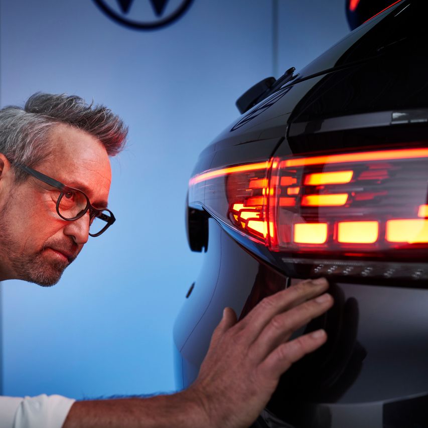 Ein Volkswagen Service-Mitarbeiter überprüft die Rückleuchten eines Volkswagens