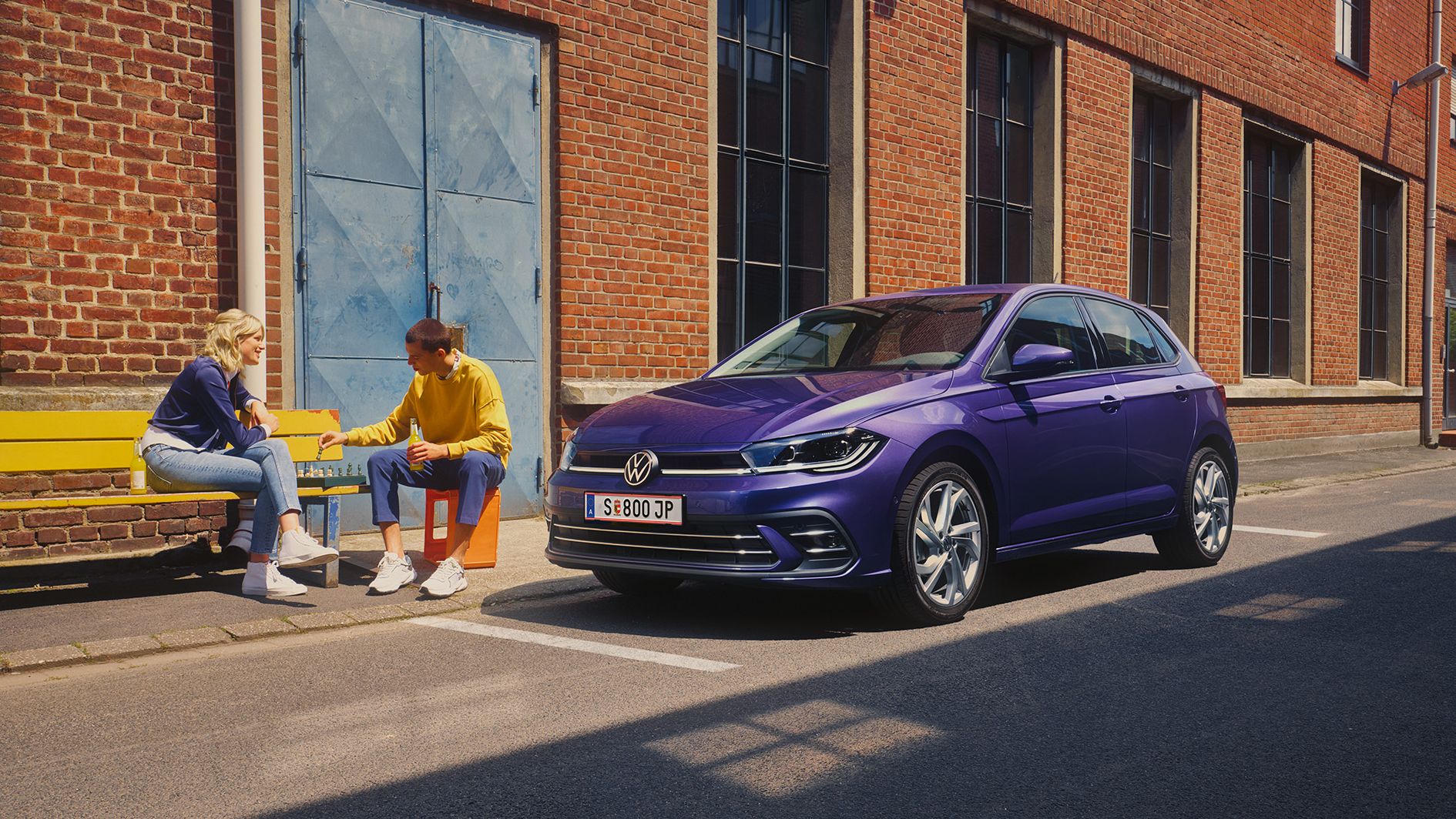 Der VW Polo Style in violetter Lackierung geparkt vor Industriegebäude