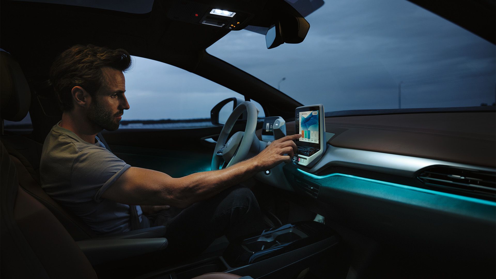 Mann sitzt auf der Fahrerseite des VW ID.4 und bedient den Touchscreen