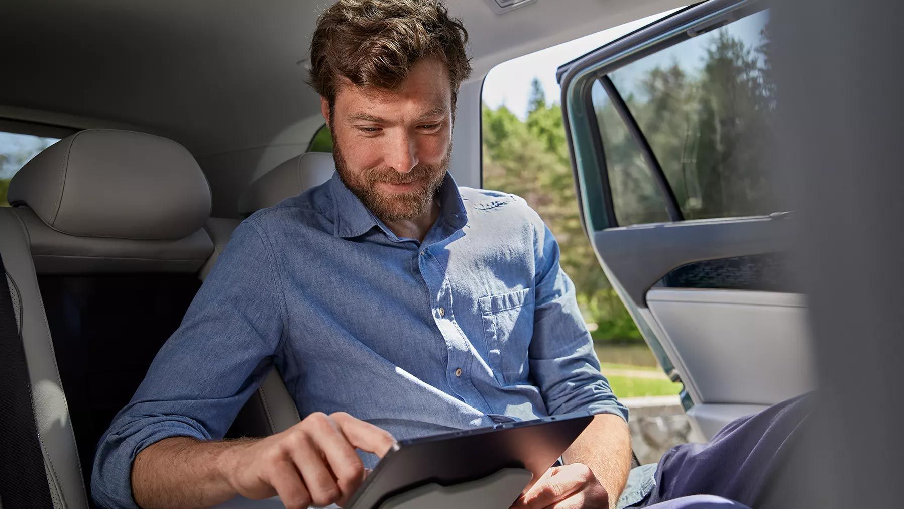 Mann sitzt auf Rückbank im VW Passat und bedient Tablet das in der Halterung befestigt ist