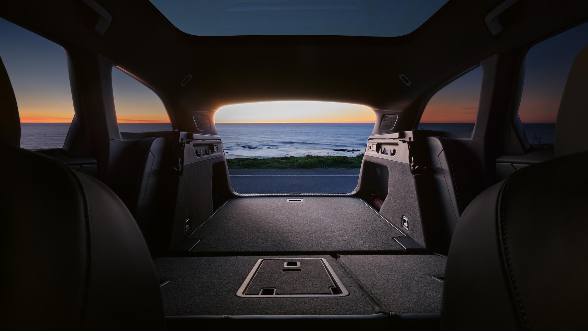 Umgeklappte Rücksitzbank und Kofferraum des VW ID.7 Tourer, im Hintergrund das Meer und ein Sonnenuntergang
