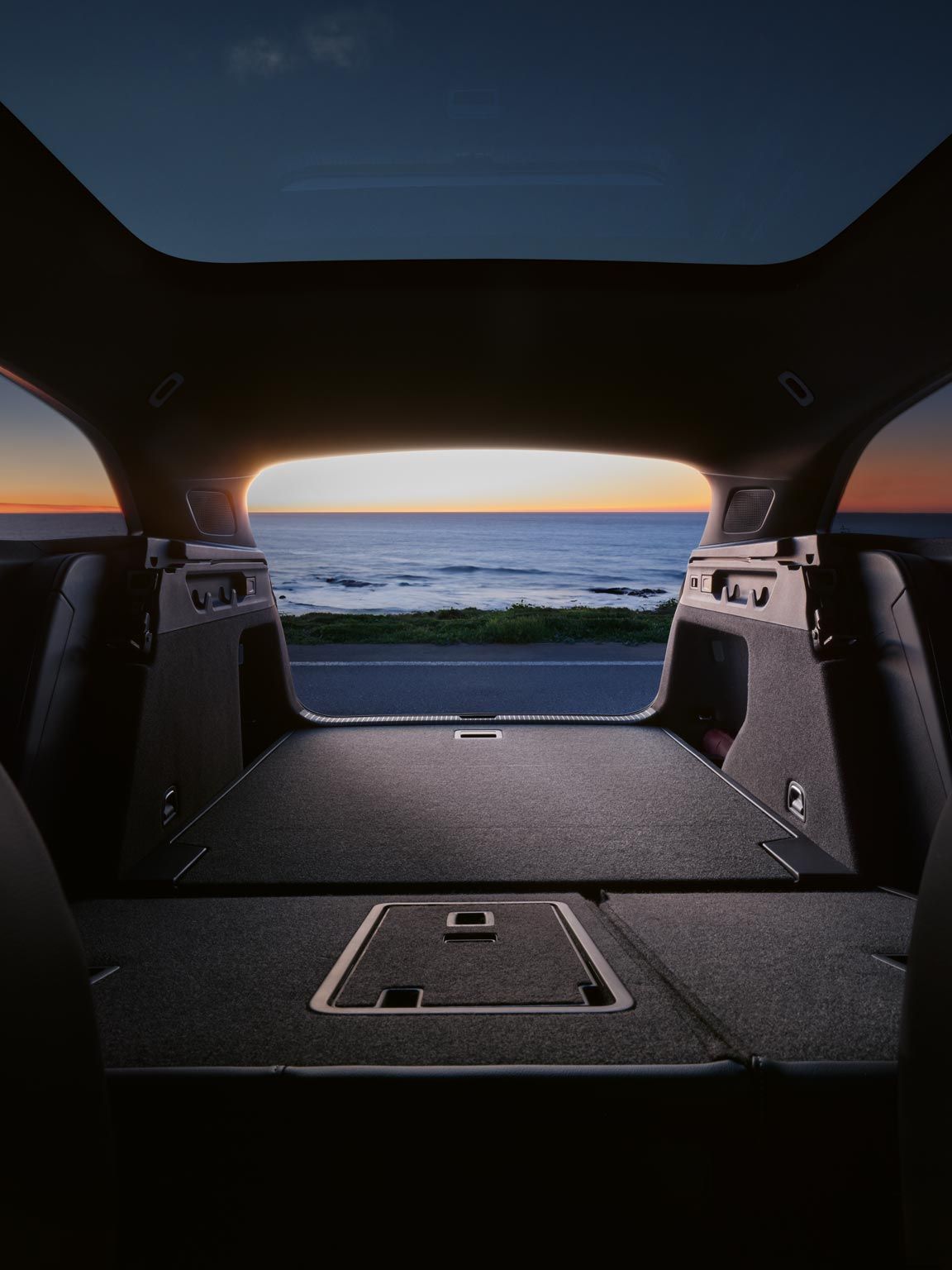 Umgeklappte Rücksitzbank und Kofferraum des VW ID.7 Tourer, im Hintergrund das Meer und ein Sonnenuntergang