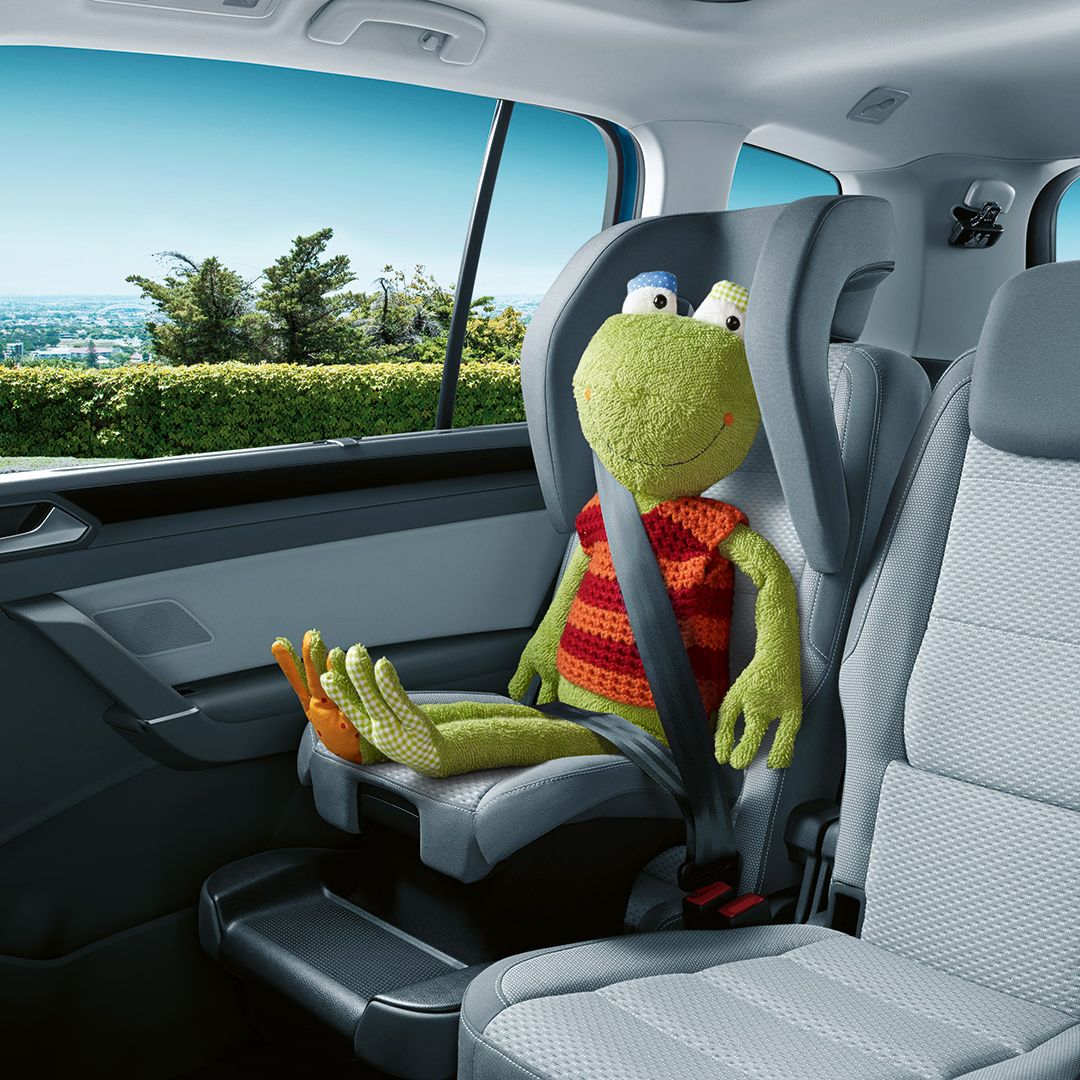 Ein Frosch-Kuscheltier sitzt auf dem integrierten Kindersitz des VW Touran. 