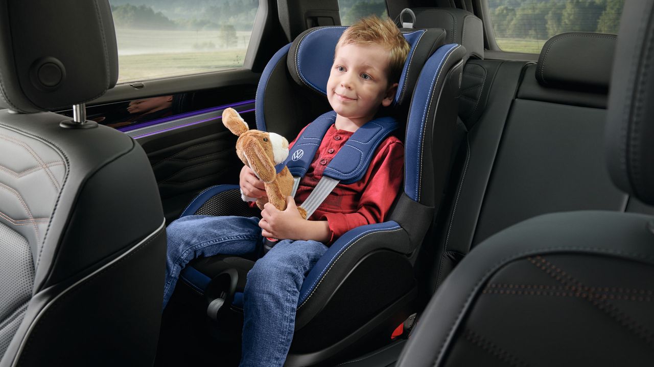 Abbildung des VW i-SIZE Kindersitzes, ein Junge mit einem Kuscheltier sitzt darin
