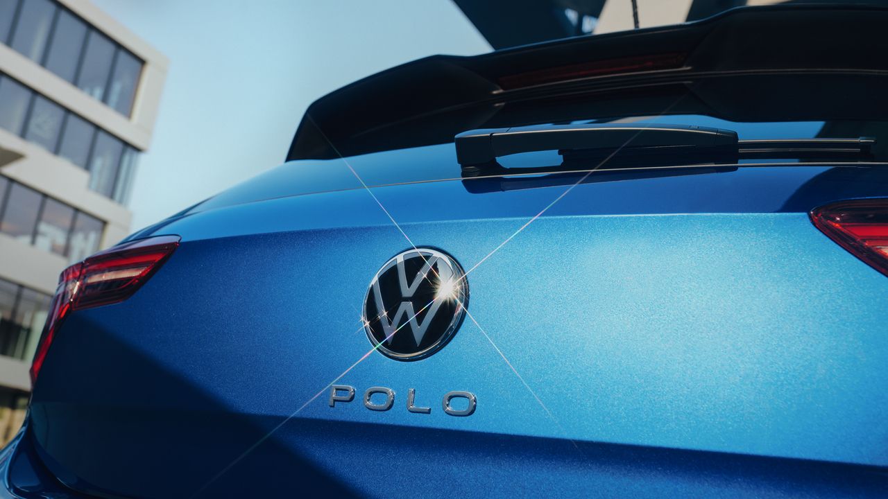 Detailansicht des VW Emblem und "Polo"-Schriftzugs auf der Heckklappe eines blauen Polo. 