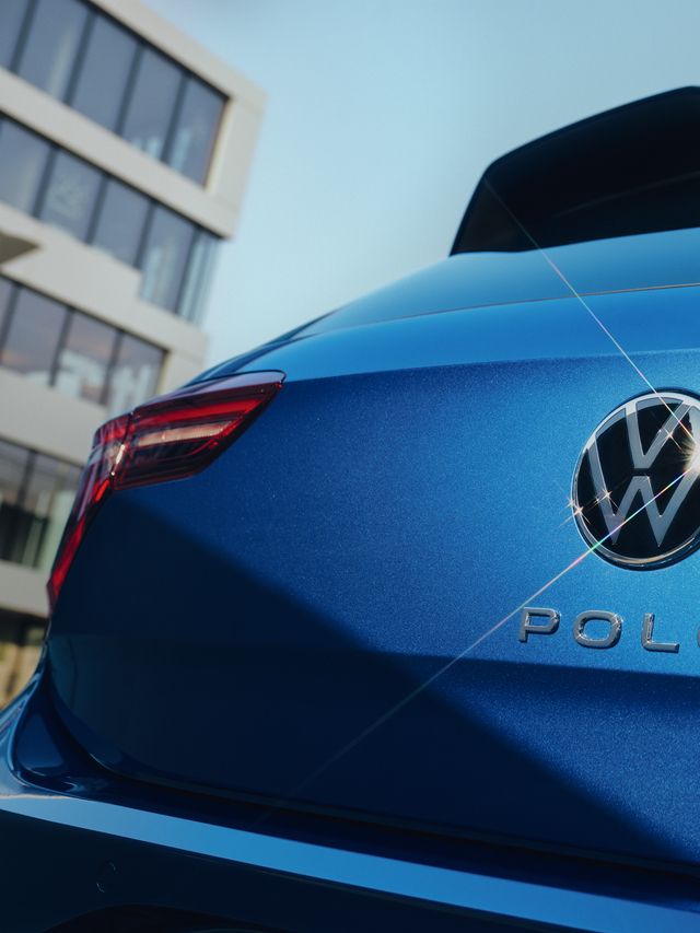 Detailansicht des VW Emblem und "Polo"-Schriftzugs auf der Heckklappe eines blauen Polo. 
