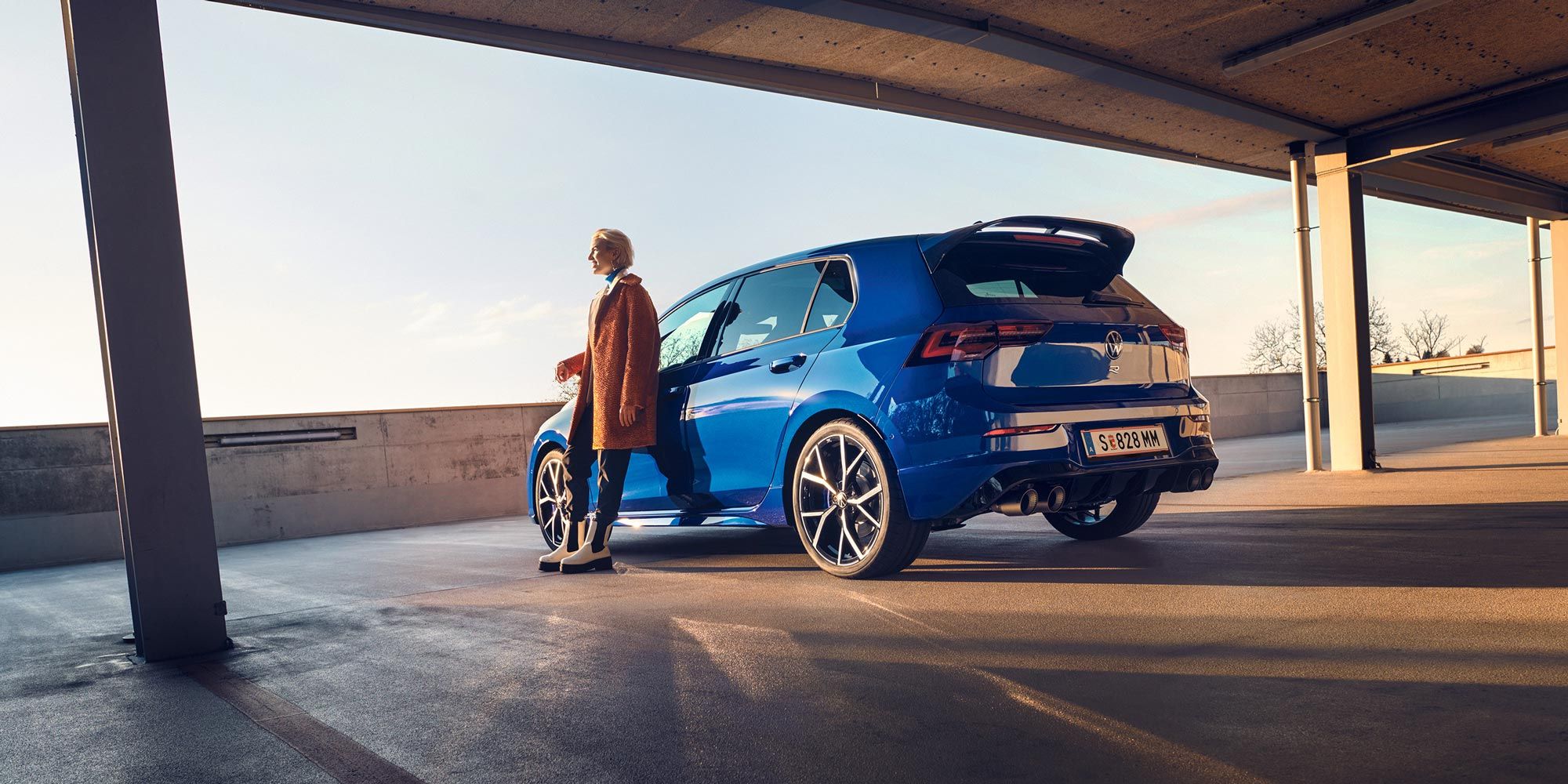 Frau lehnt sich an blauen VW Golf R