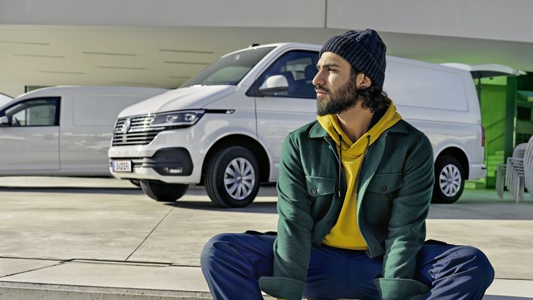 Mann sitzt vor einem VW Transporter im Hintergrund