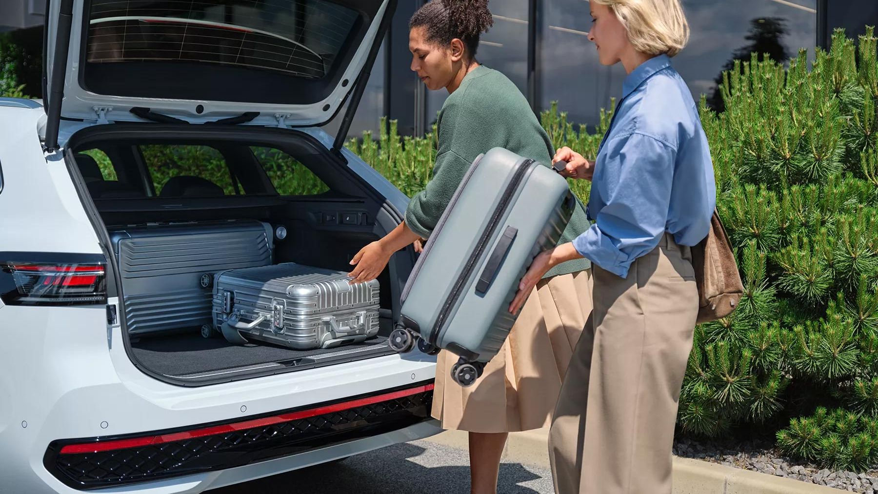 Zwei Frauen legen ihre Koffer in den großzügigen Kofferraum des VW Passat