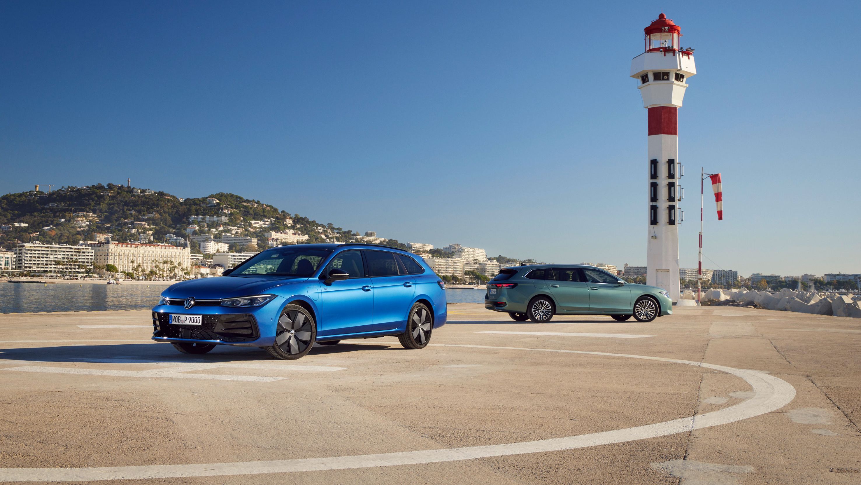 Ein blauer und ein grüner VW Passat stehen auf einem Landeplatz am Meer. 