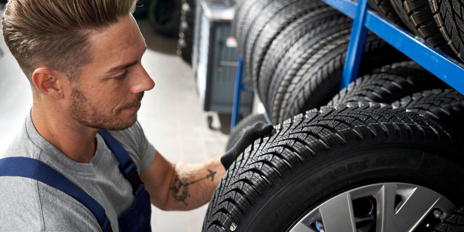 Ein Volkswagen Service Techniker nimmt einen Reifen aus einem Lagerregal