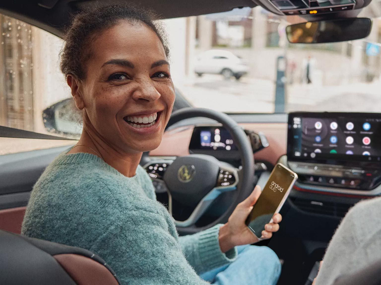 Frau lächelnd mit Smartphone in der Hand nutzt Android Auto im ID.
