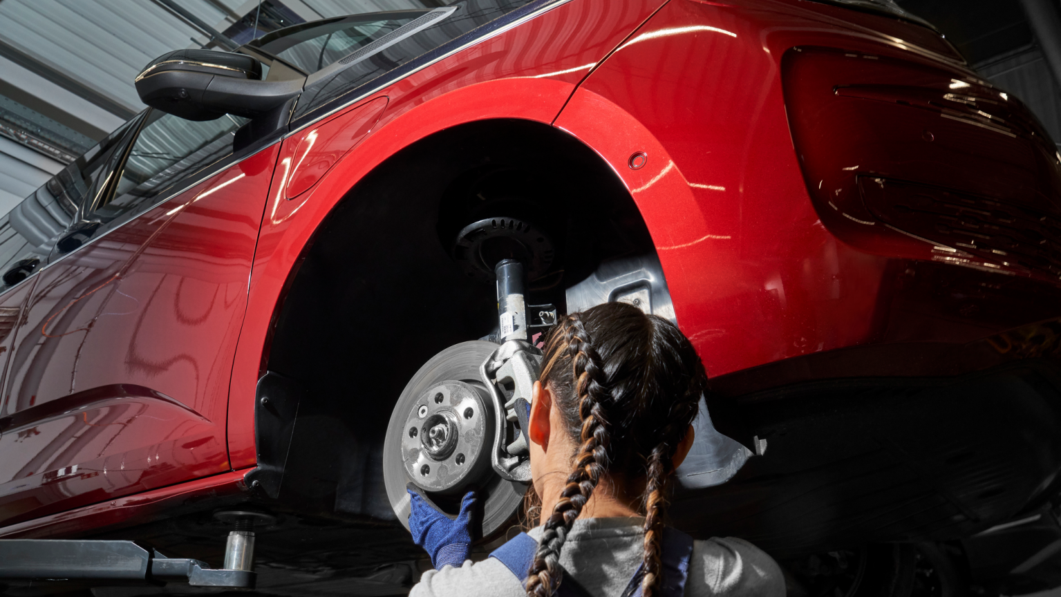 Eine VW Mechanikerin wechselt die Bremsscheiben bei einem VW Nutzfahrzeug