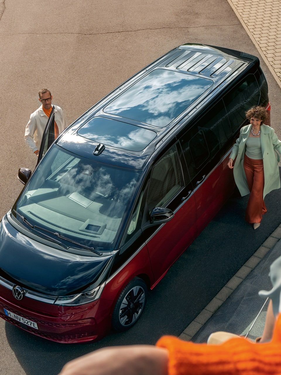 Eine Frau blickt in die Kamera, im Hintergrund ein VW Multivan