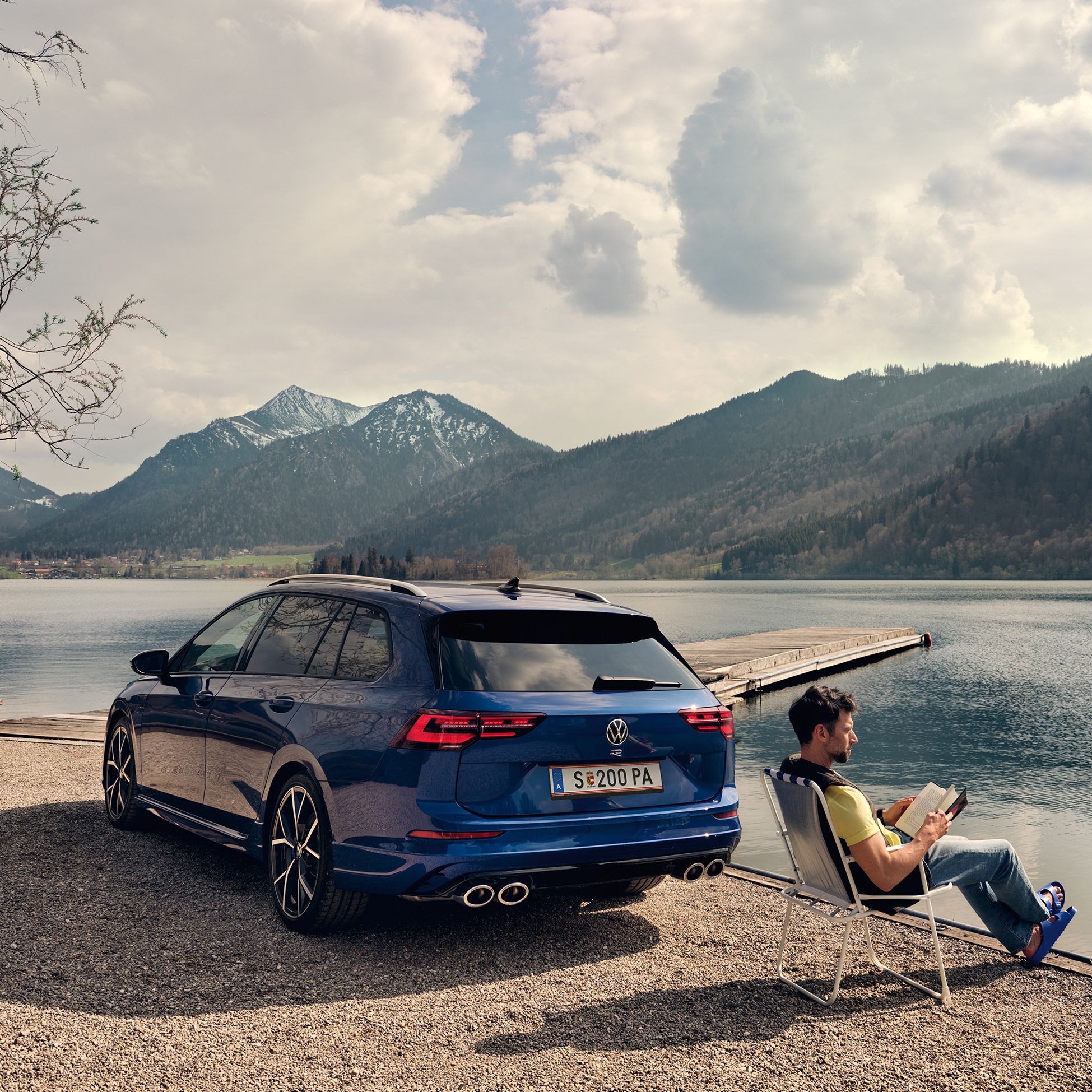 VW Golf R Variant steht an einem See, daneben sitzt ein Mann in einem Campingstuhl