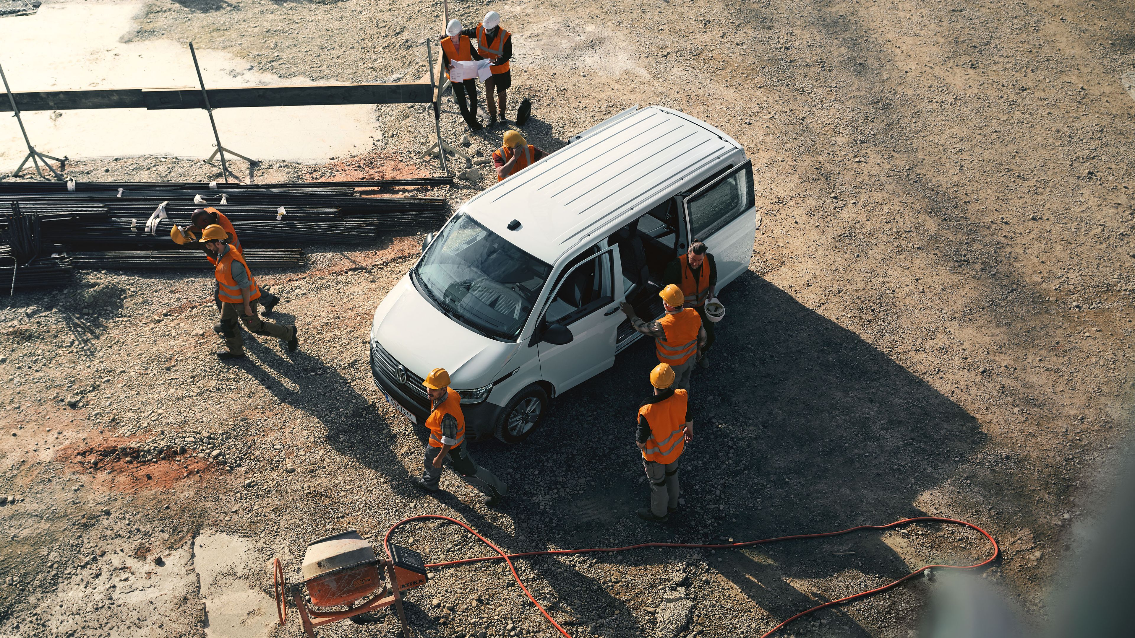weißer VW Transporter 6.1 Kombi auf Baustelle mit Bauarbeitern Vogelperspektive