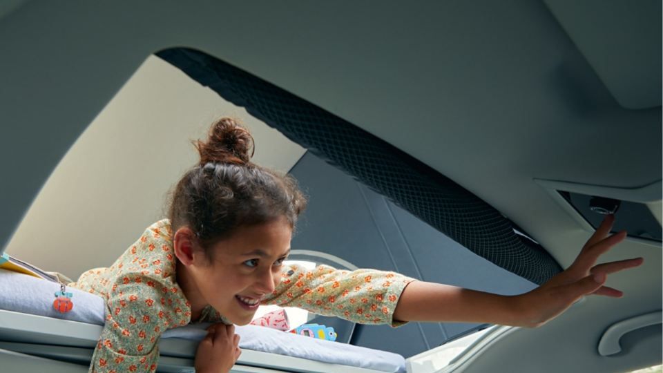 Ein Mädchen liegt im Dachbett eines VW California 6.1