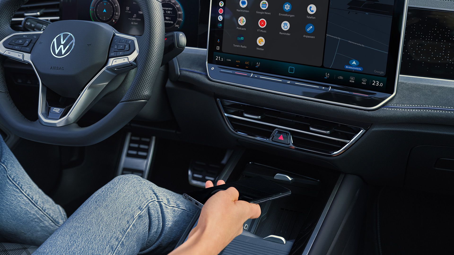 Detailansicht auf das Cockpit des VW Passast. Eine Person auf dem Fahrersitz hält ein Smartphone in der Hand.