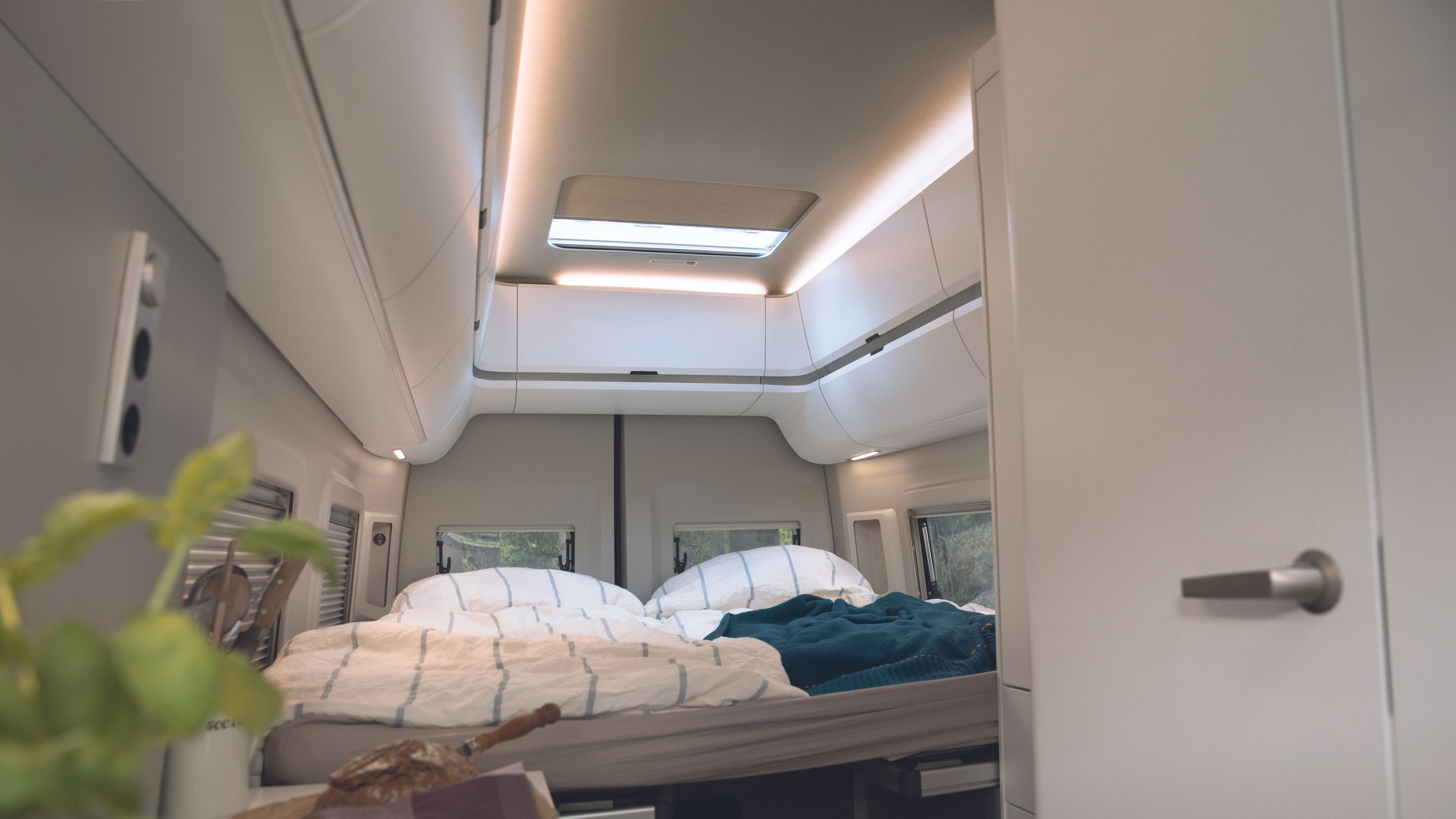 Bild zeigt das Bett im Grand California 680 mit gemütlicher Innenraumbeleuchtung. 