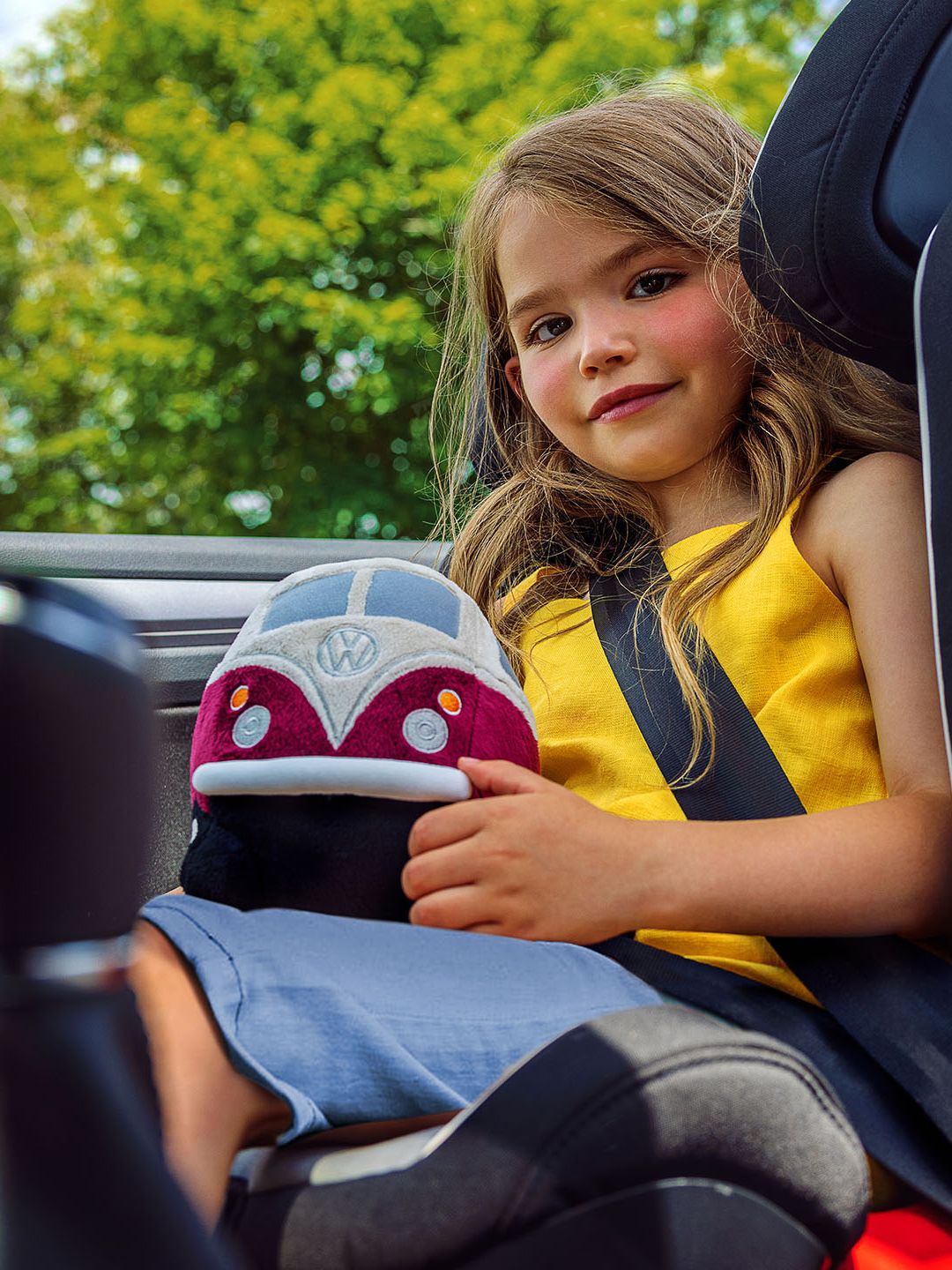 Ein Mädchen im Kindersitz mit einem VW Plüsch Bulli am Schoß