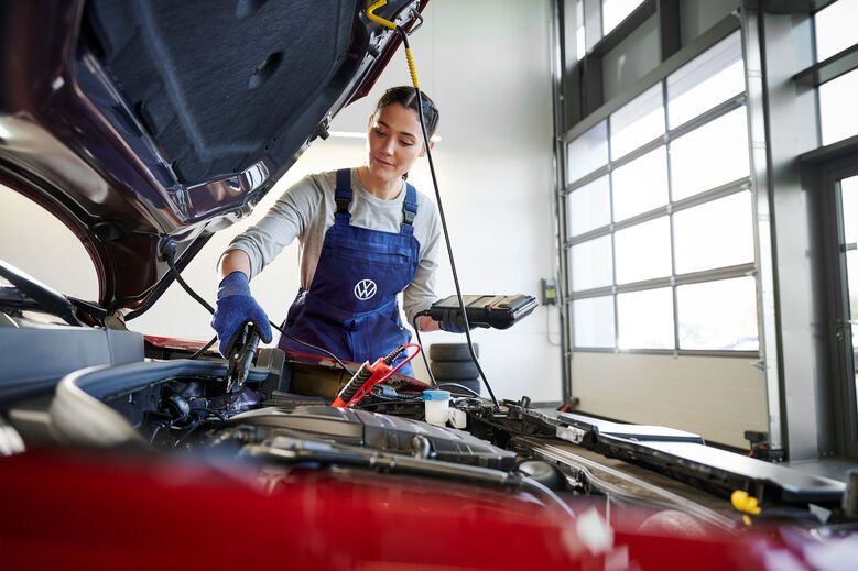 Volkswagen Service Technikerin vor geöffneter Motorhaube