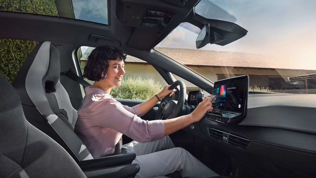 Frau sitzt in VW ID.3 und bedient Touch-Display