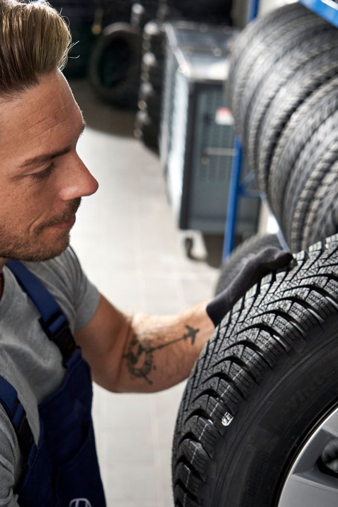 Ein Volkswagen Service Techniker nimmt einen Reifen aus einem Lagerregal