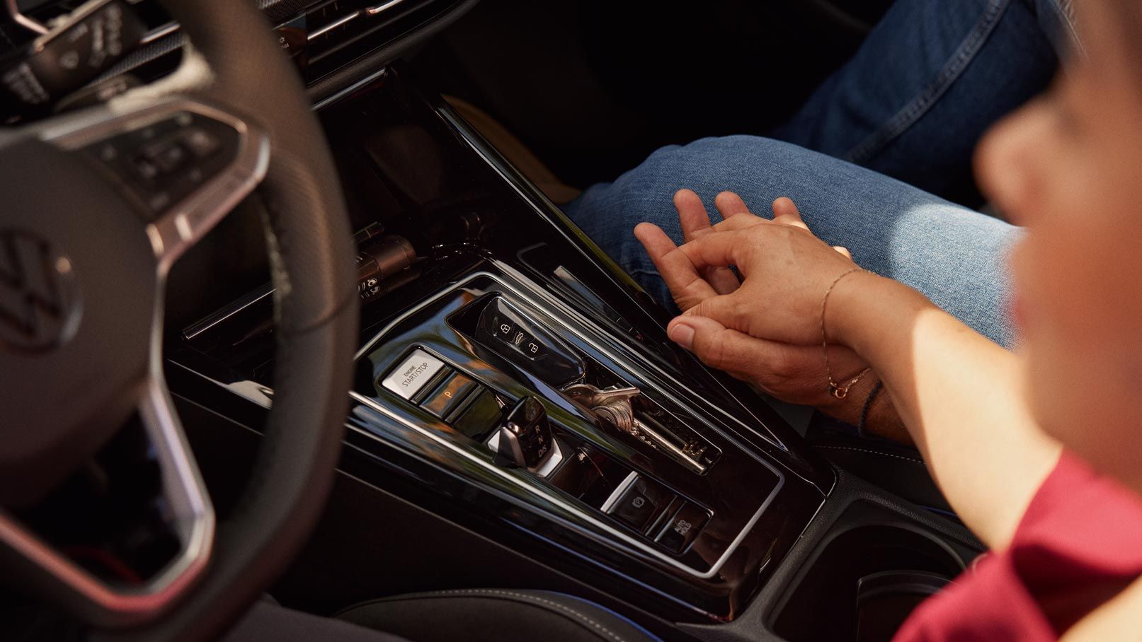 Detailansicht der Mitellkonsole und DSG/Automatikgetriebe im VW Golf, zwei Menschen halten Hände