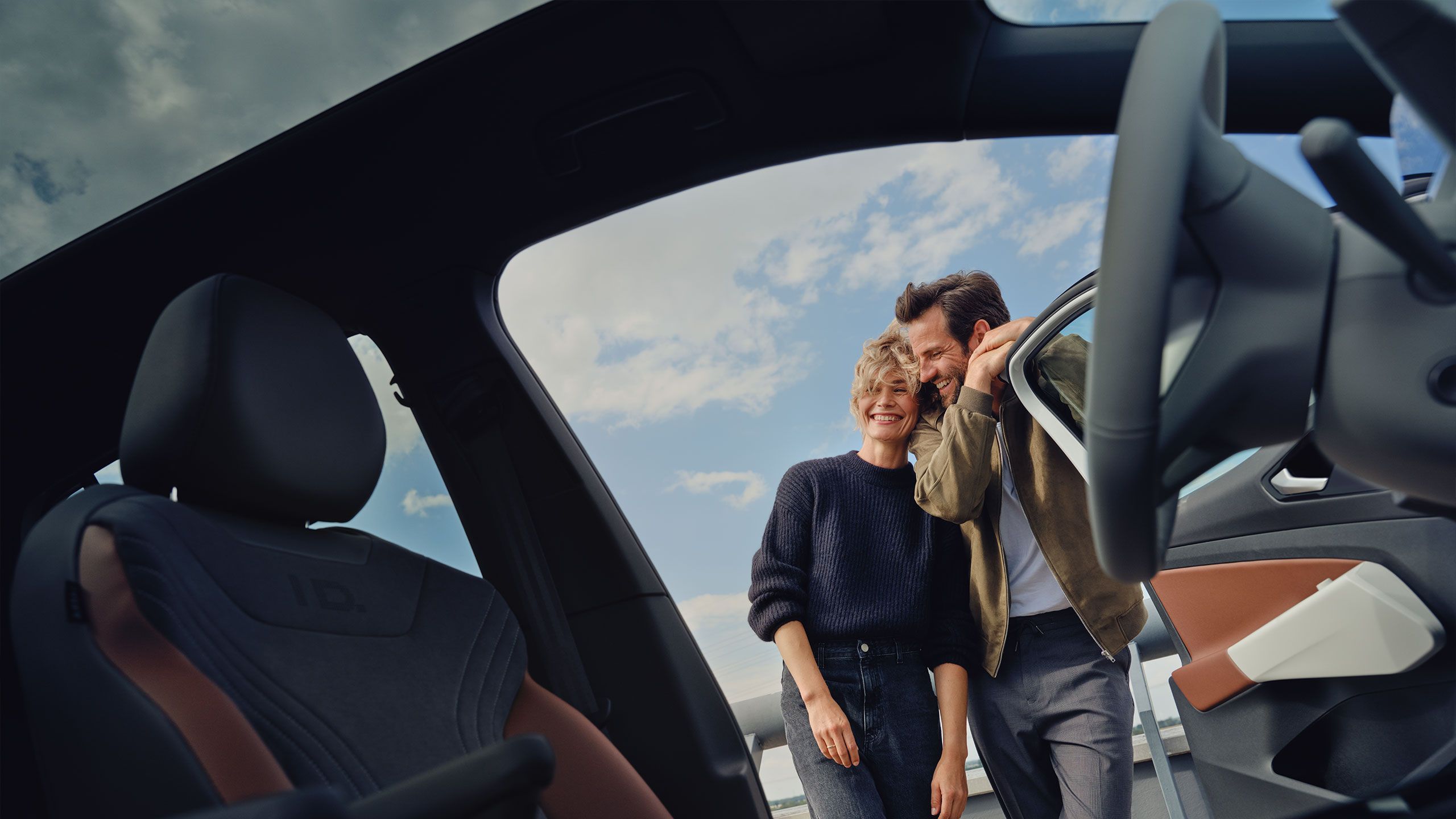Blick aus dem Cockpit eines Volkswagen, ein Mann und eine Frau stehen außerhalb des Fahrzeuges