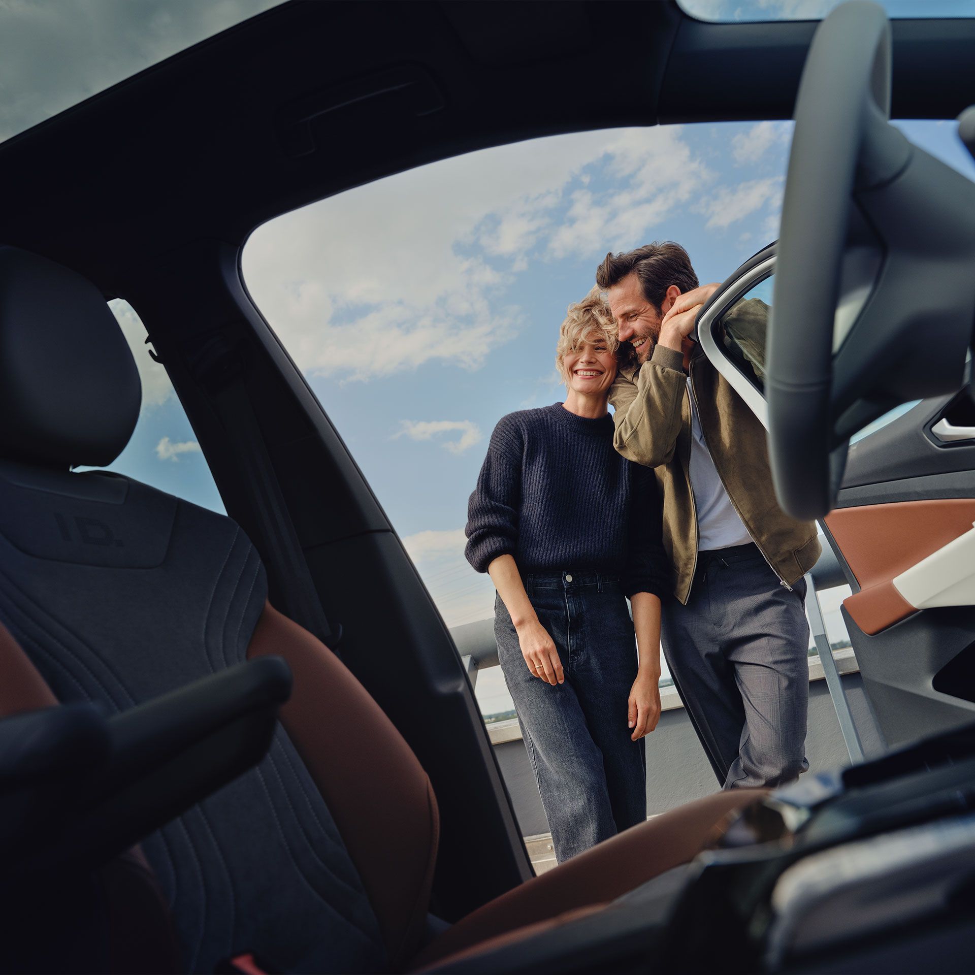 Blick aus dem Cockpit eines Volkswagen, ein Mann und eine Frau stehen außerhalb des Fahrzeuges