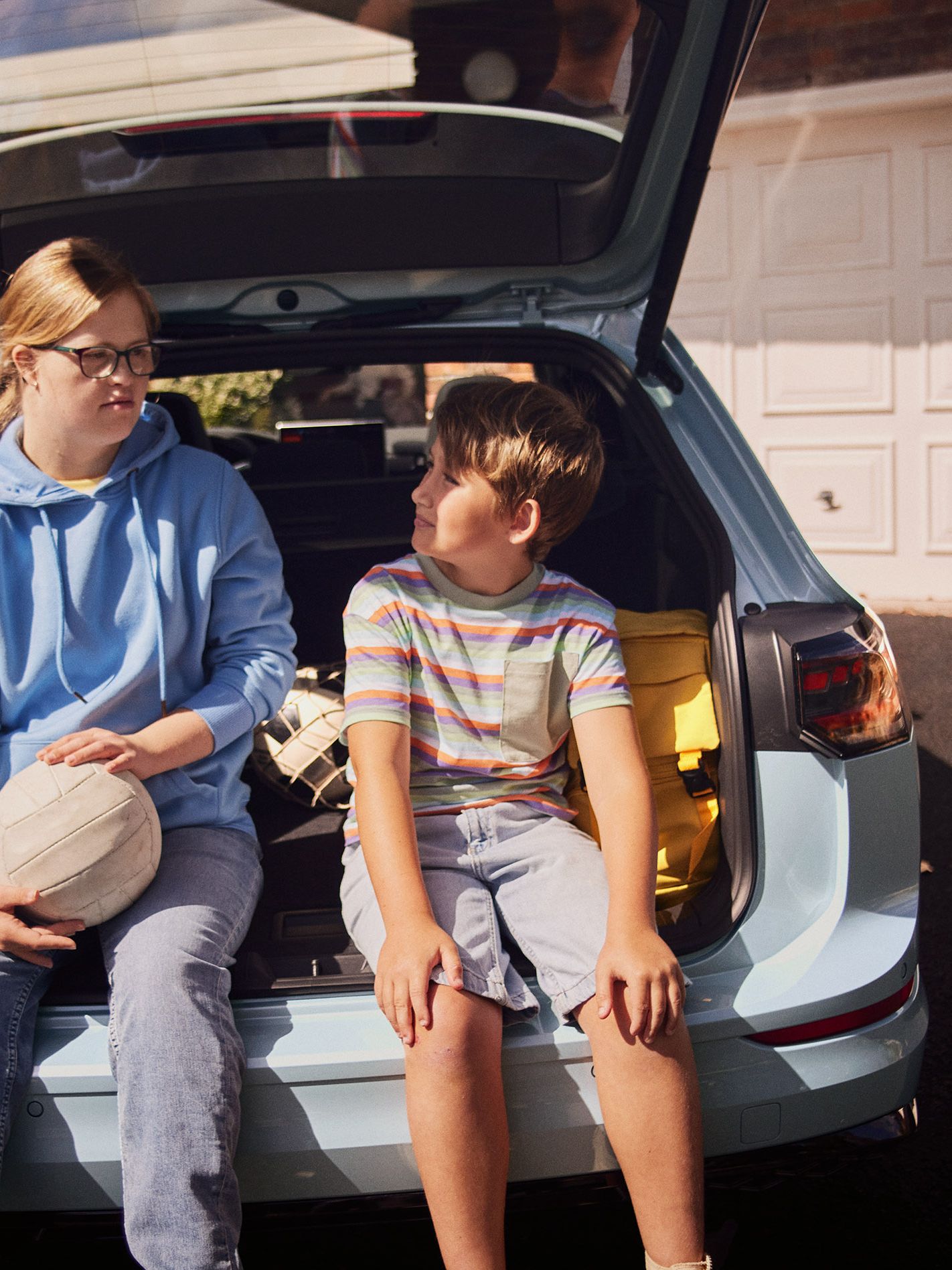 Junge und Mädchen sitzen im Kofferraum des VW Golf Variant