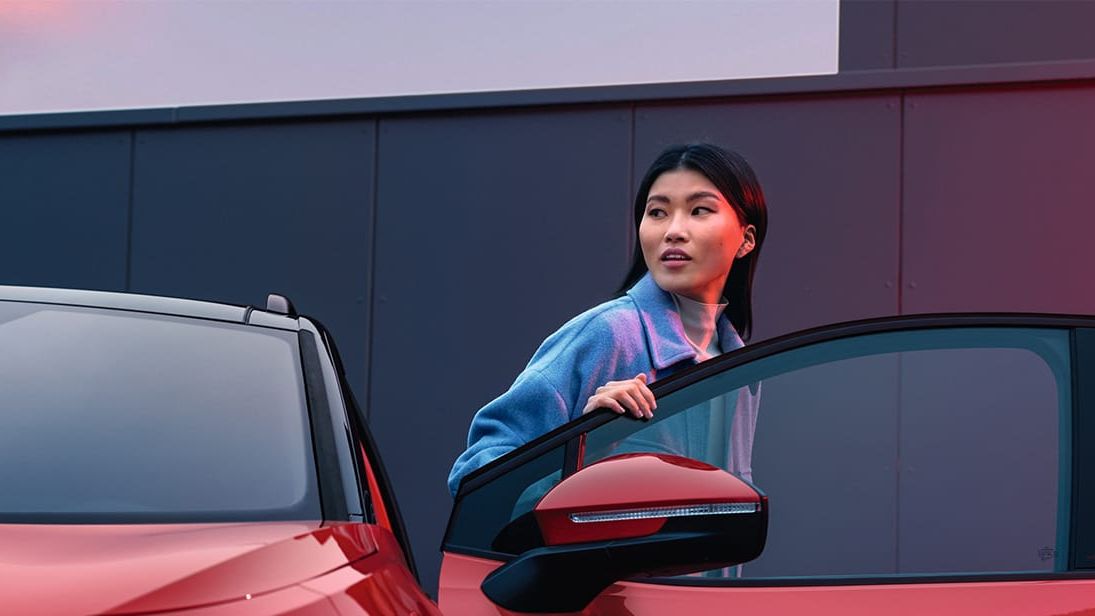 Frau steigt aus einem roten VW ID.4 GTX