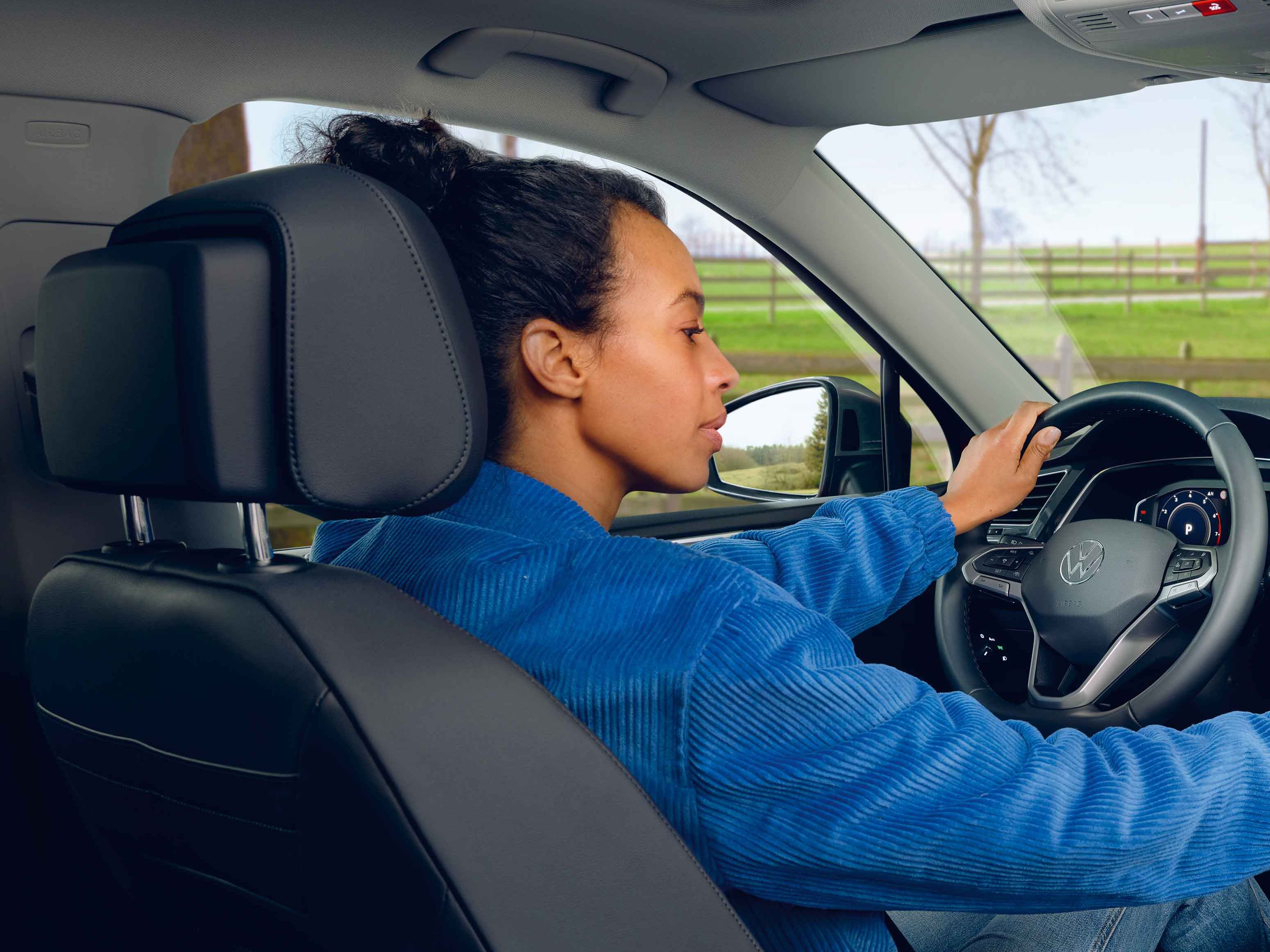 Eine Frau sitzt auf dem Fahrersitz des VW Tiguan Allspace und bedienet das Navigationssystem