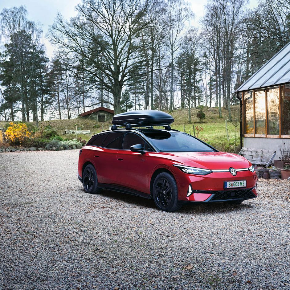 Ein roter VW ID.7 Tourer GTX mit Dachbox in ländlicher Umgebung