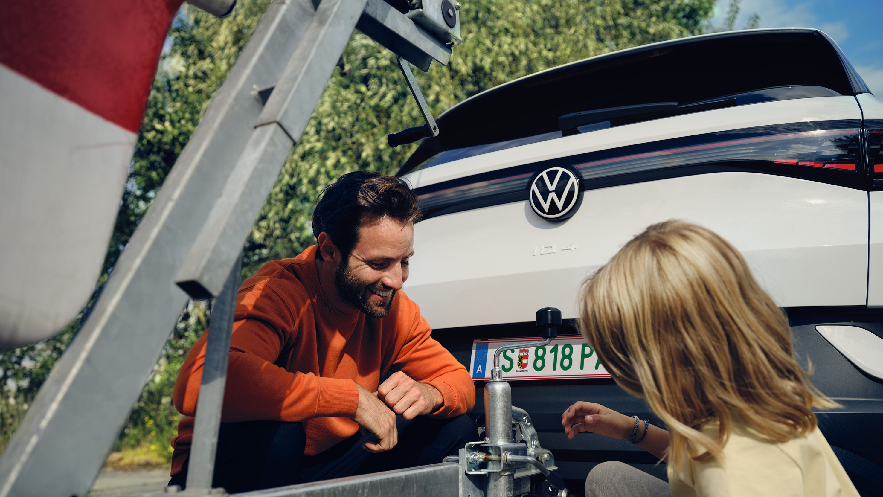 Tochter und Vater und montieren Anhänger am VW ID.4