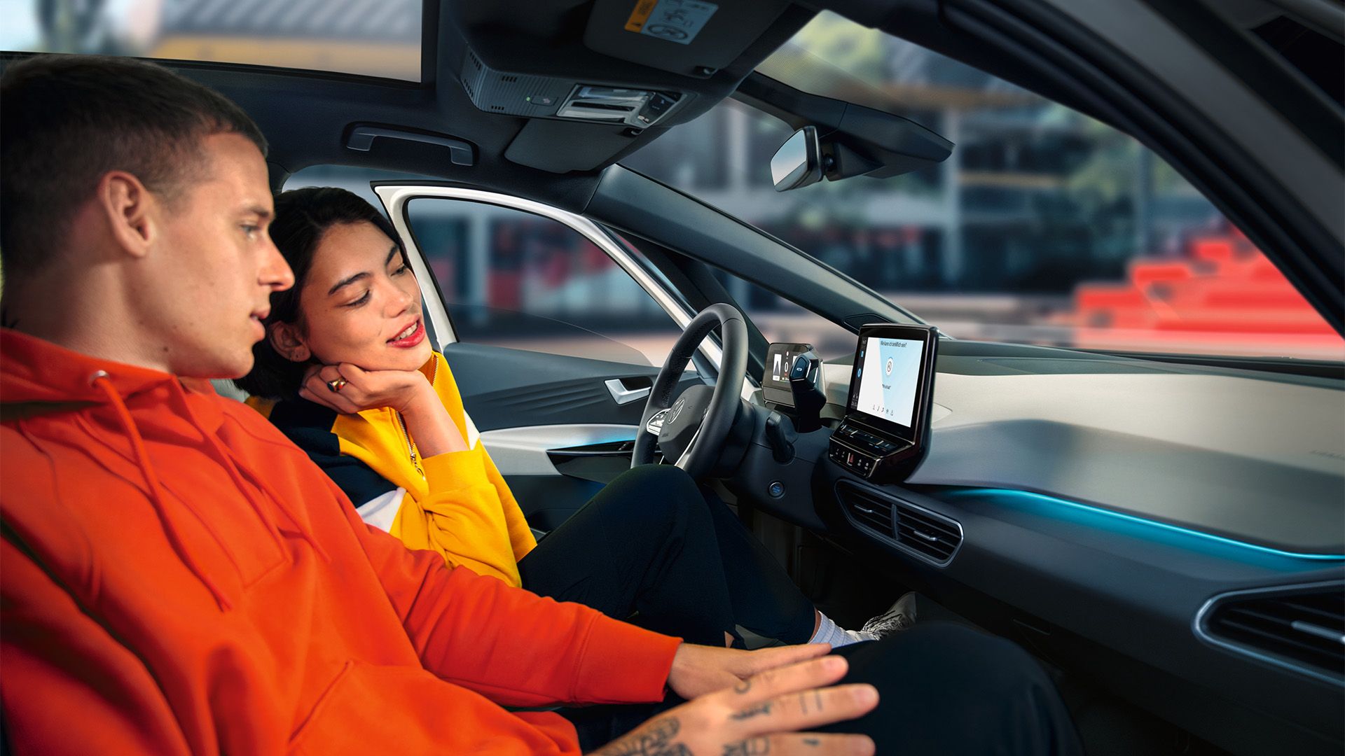 Junge Frau und junger Mann sitzen auf den vorderen Plätzen des VW ID.3 und schauen auf den Touchscreen