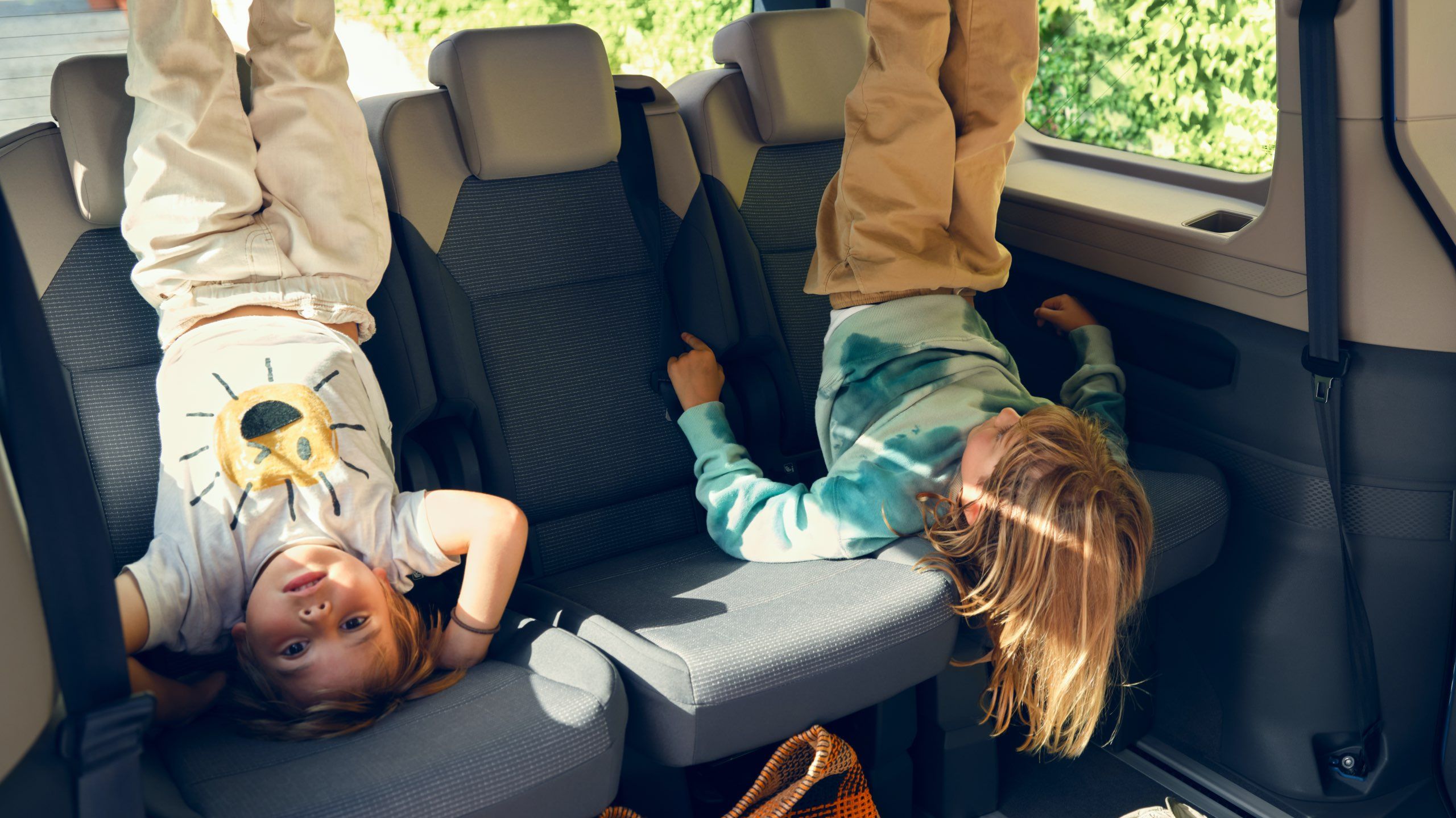 Zwei Kinder liegen auf den Einzelsitzen des neuen VW Multivan T7 2021 und strecken Ihre Beine in die Luft.