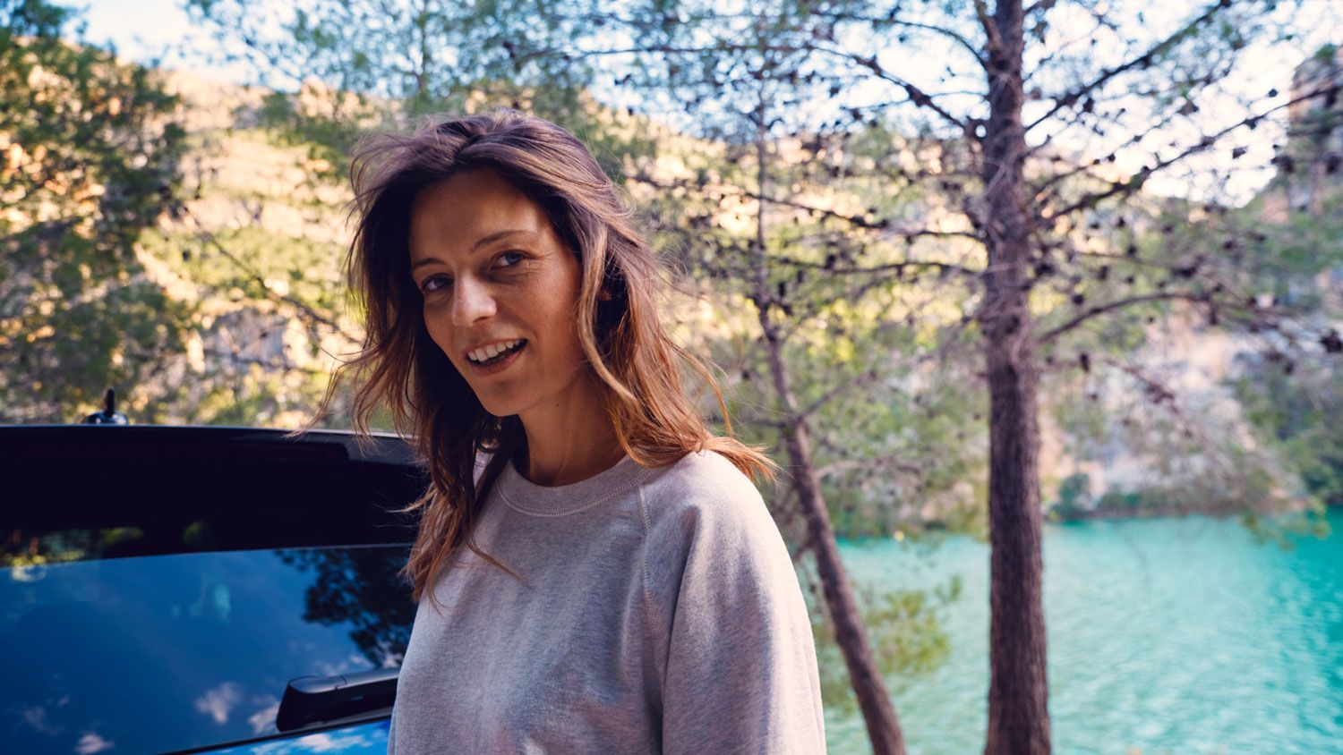 Eine Frau steht lächelnd hinter einem VW Touareg R eHybrid