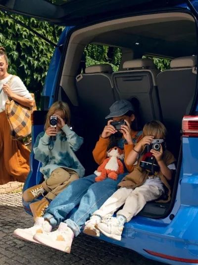 VW-Multivan mit geöffneter Heckklappe-drei Kinder sitzen in der Öffnung