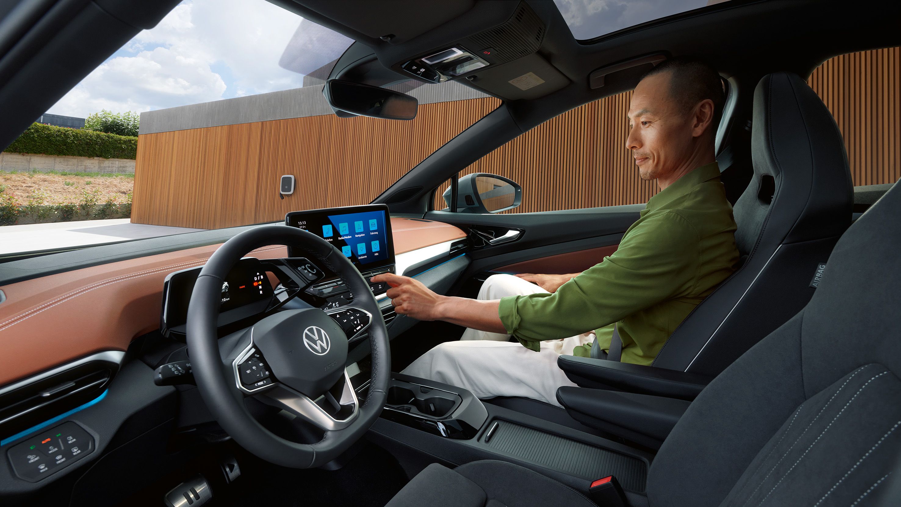 Seitlicher Blick auf die Vordersitze eines VW ID.5, auf dem Vordersitz bedient ein Mann das Infotainment-System