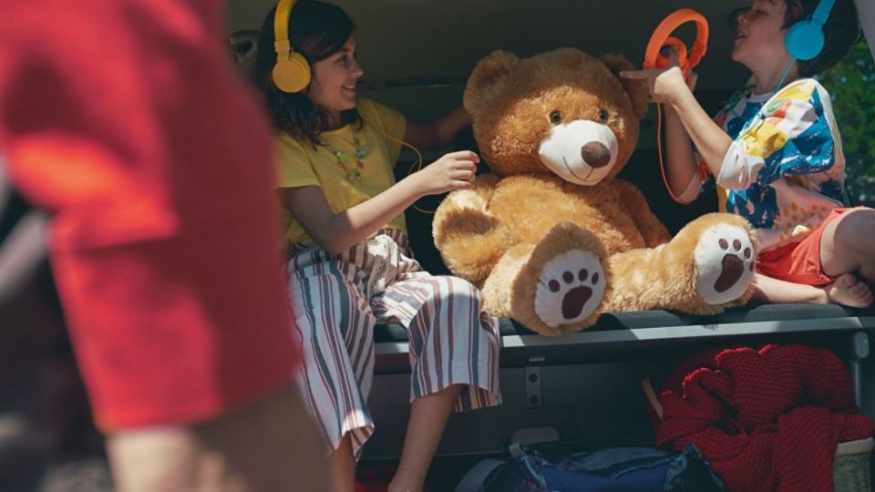Zwei Kinder sitzen auf klappbarer 3er-Sitzbank im Fahrgastraum eines VW Multivan 6.1..
