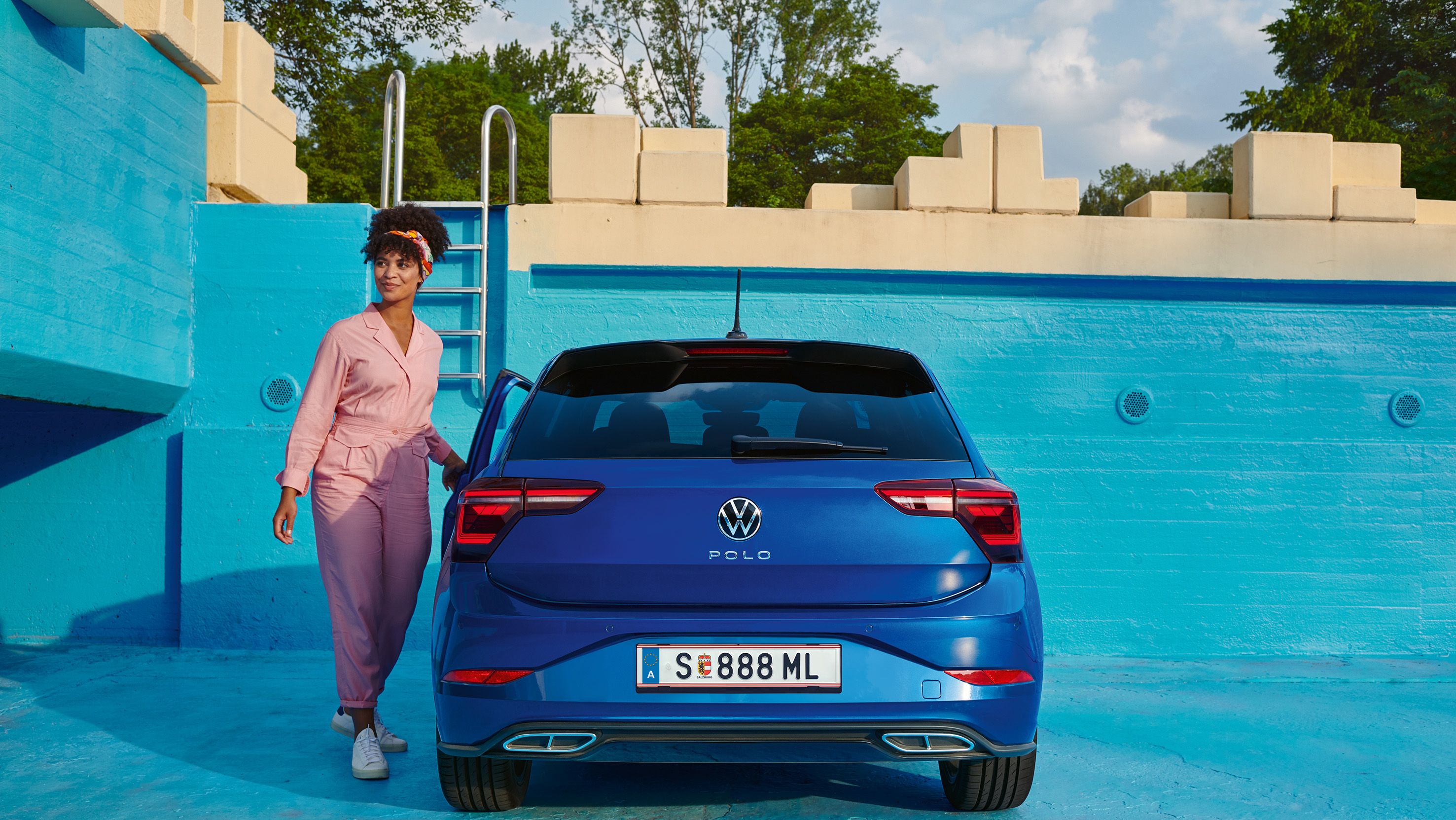 Blick auf das Heck eines blauen VW Polo, gepark tin einem leeren Pool. 