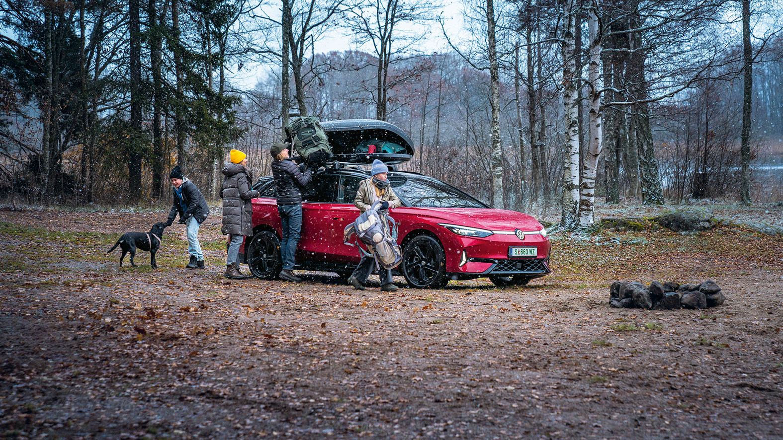 Eine Familie mit ihrem roten VW ID.7 Tourer GTX im Wald